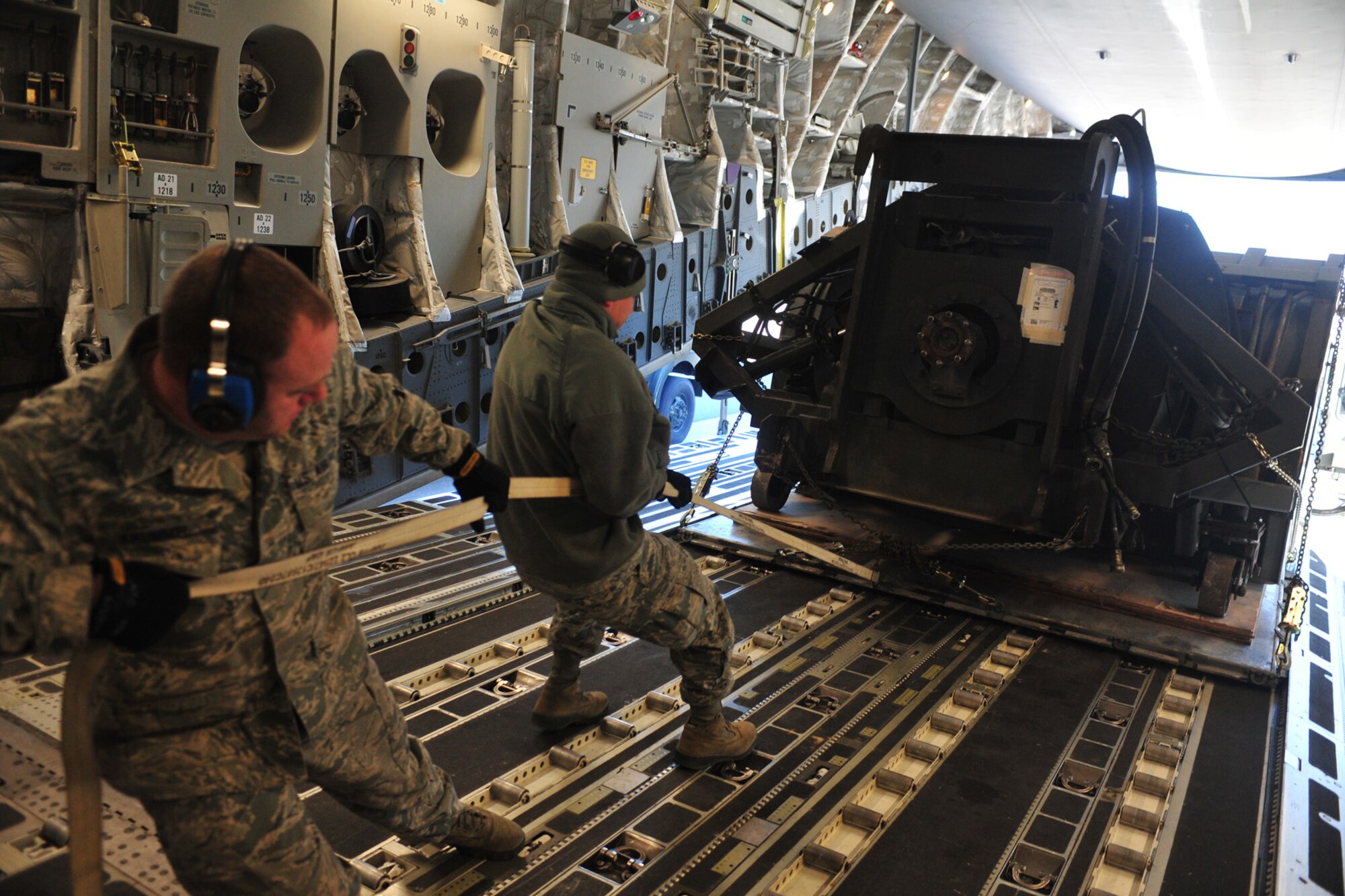 Staff Sgt. Brandon Edwards, 92nd Logistics Readiness Squadron air transportation journeyman, and Tech. Sgt. Jeffery Krummel, 92nd LRS NCO in charge of small air terminal, pull a palletized piece of snow blowing equipment onto a C-17 Globemaster III at Fairchild Air Force Base, Wash., Dec. 4, 2013. The equipment will be delivered to the Transit Center at Manas, Kyrgyzstan, in preparation for the incoming weather. (U.S. Air Force photo by Senior Airman Taylor Curry/Released)