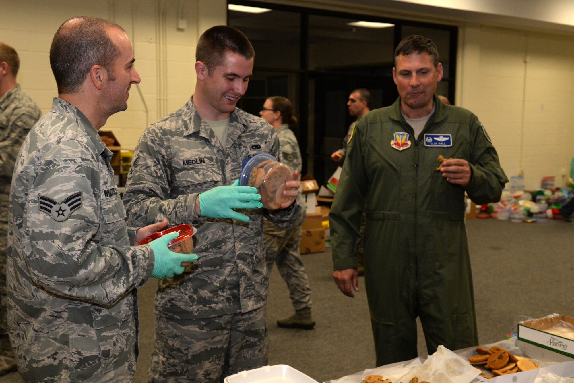 U.S. Air Force Col. Clay Hall, 20th Fighter Wing commander, right, samples a donated cookie and talks to two Airman Leadership School students during the annual cookie drive, Dec. 5, 2013, at Shaw Air Force Base, S.C. The cookies were donated by the Sumter, S.C. community and distributed on base to the single Airmen and Soldiers living in the dorms.  (U.S. Air Force photo by Airman 1st Class Jonathan Bass/Released)