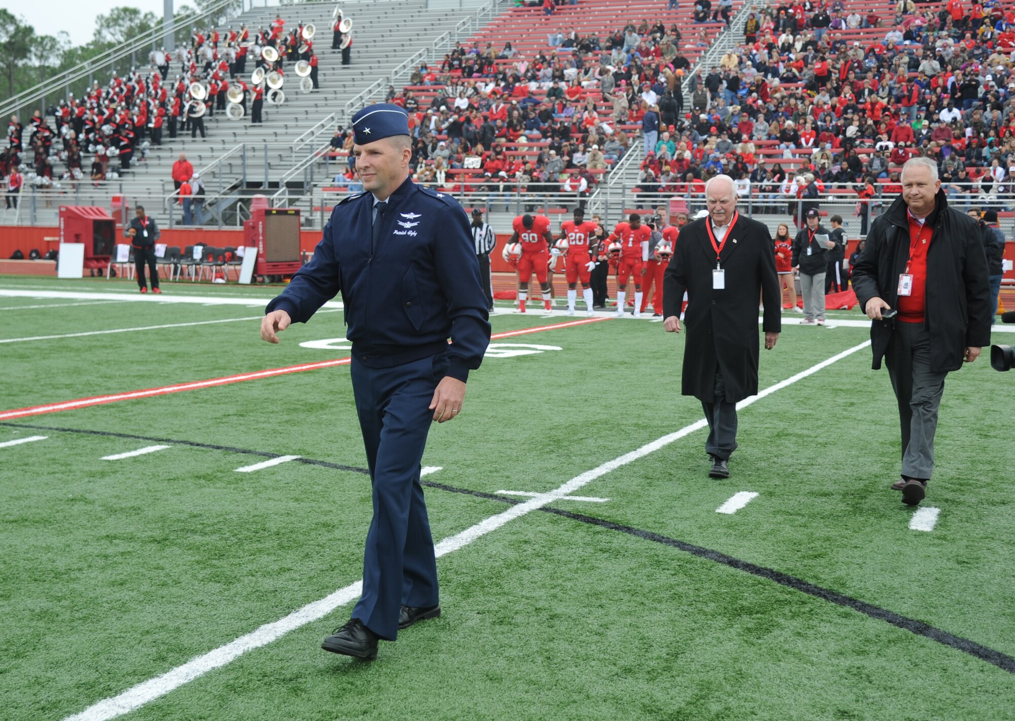 Brig. Gen. Patrick Higby, 81st Training Wing commander, Keesler Air Force Base, Miss., is followed by Dub Herring and Barry Harper, as they take their place on the field for the coin toss during a pre-game celebration at the 2013 Mississippi Bowl, Biloxi High School football stadium Dec. 8, 2013. The Keesler Honor Guard and Airmen carrying the 50-State flags also participated in the pre-game celebration.  (U.S. Air Force photo by Kemberly Groue)