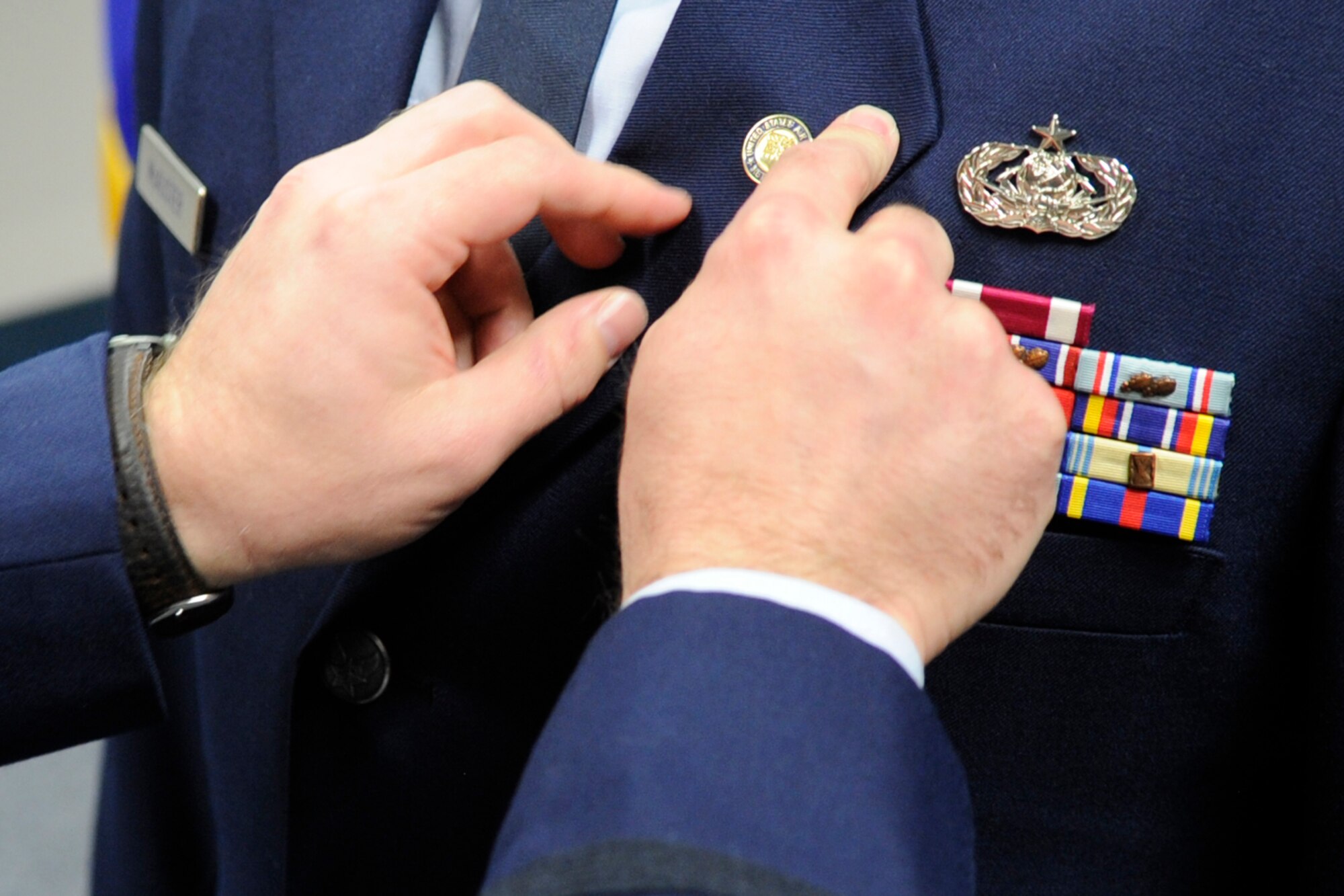 U.S. Air Force Maj. Justin L. Kunath, senior duty officer, 624th Operations Center, places a retirement pin on the lapel of Master Sgt. Robert D. McAlister during a retirement ceremony at Barksdale Air Force Base, La., Dec. 7, 2013. McAlister retired after more than 28 years of military service. (U.S. Air Force photo by Master Sgt. Jeff Walston) 