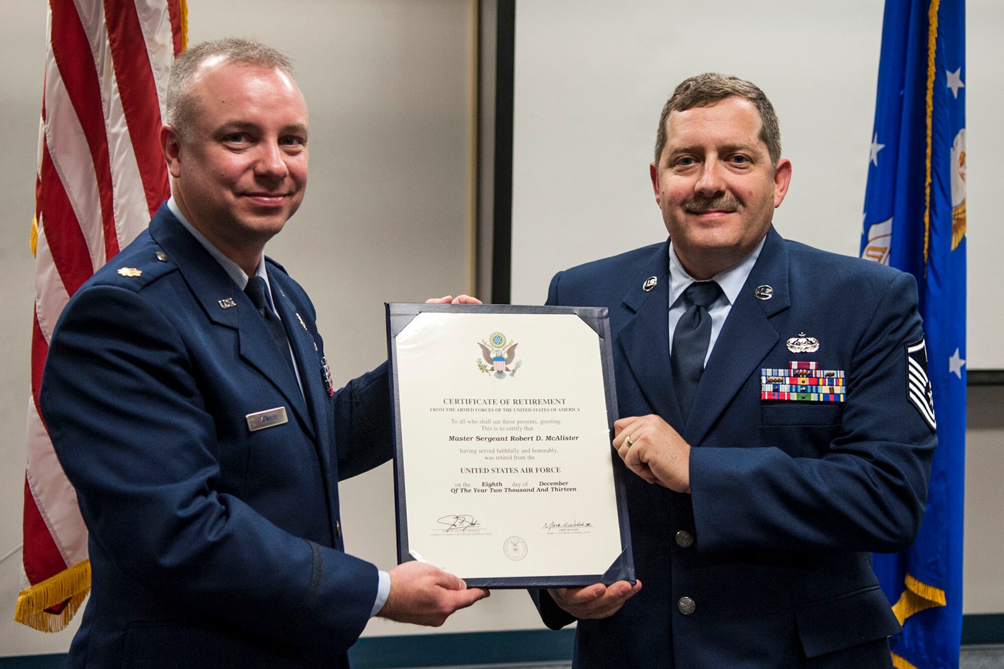 U.S. Air Force Maj. Justin L. Kunath, senior duty officer, 624th Operations Center, presents a retirement certificate to Master Sgt. Robert D. McAlister during a ceremony held at Barksdale Air Force Base, La., Dec. 7, 2013. McAlister retired after more than 28 years of military service. (U.S. Air Force photo by Master Sgt. Jeff Walston) 