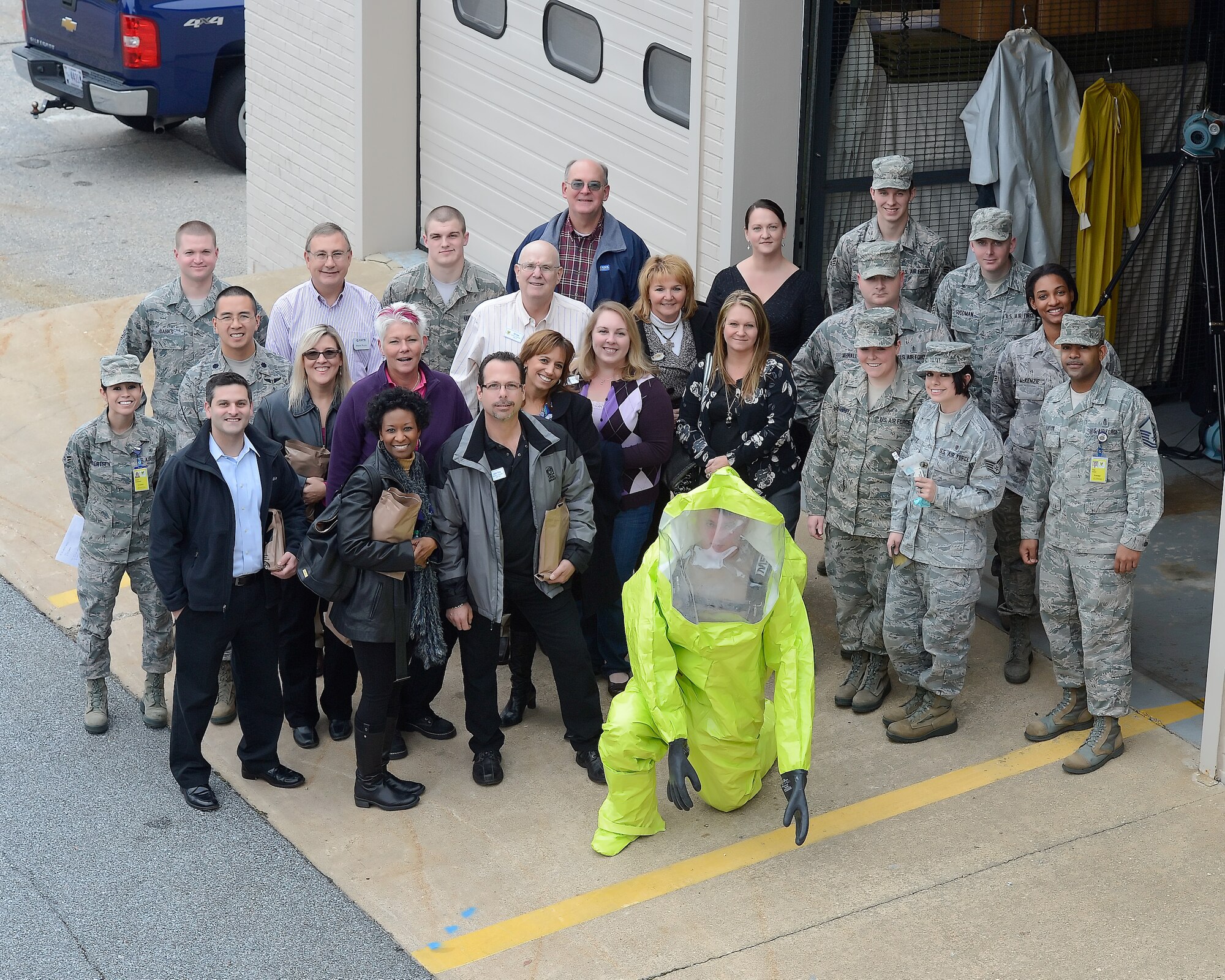 Group photo taken with military members and honorary commanders after a demonstration by the biological/environmental section of the 436th Medical Group during an in-depth tour Dec. 4, 2013, at  Dover Air Force Base, Del. At the front of the group is an airman wearing a protective suit which some honorary commanders were able to wear during the demonstration. (U.S. Air Force photo/Greg L. Davis)