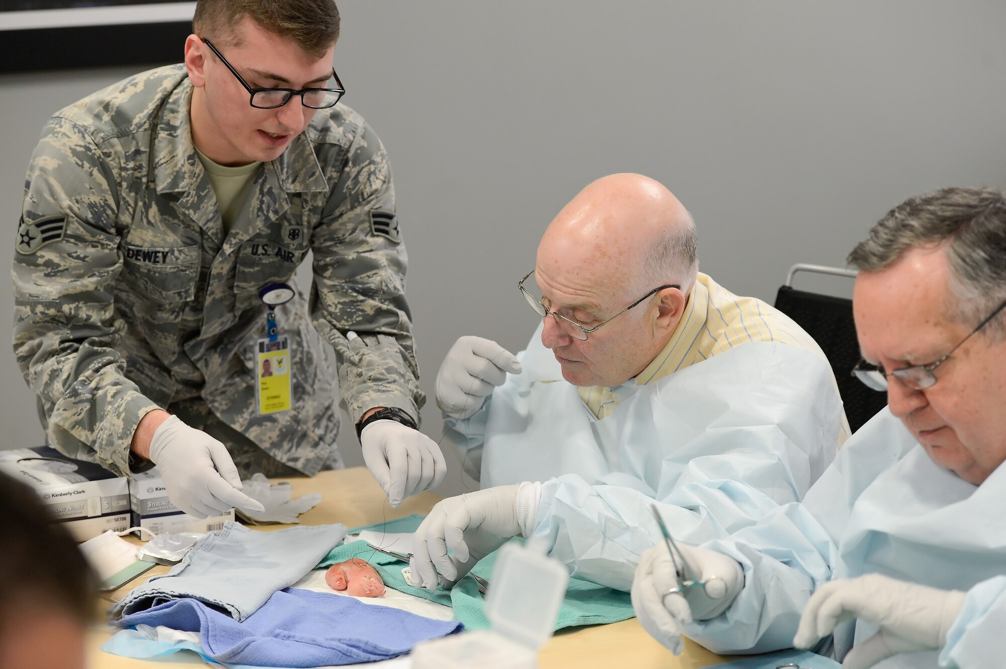 Senior Airman Paul Dewey, 436th Medical Operations Squadron, shows Bill Hare, 436th Operations Group honorary commander, how to suture a wound using a pigs foot during a tour of the 436th Medical Group Dec. 4, 2013, Dover AFB, Del. After the demonstration, each honorary commander was able to try their hand at suturing. (U.S. Air Force photo/Greg L. Davis)