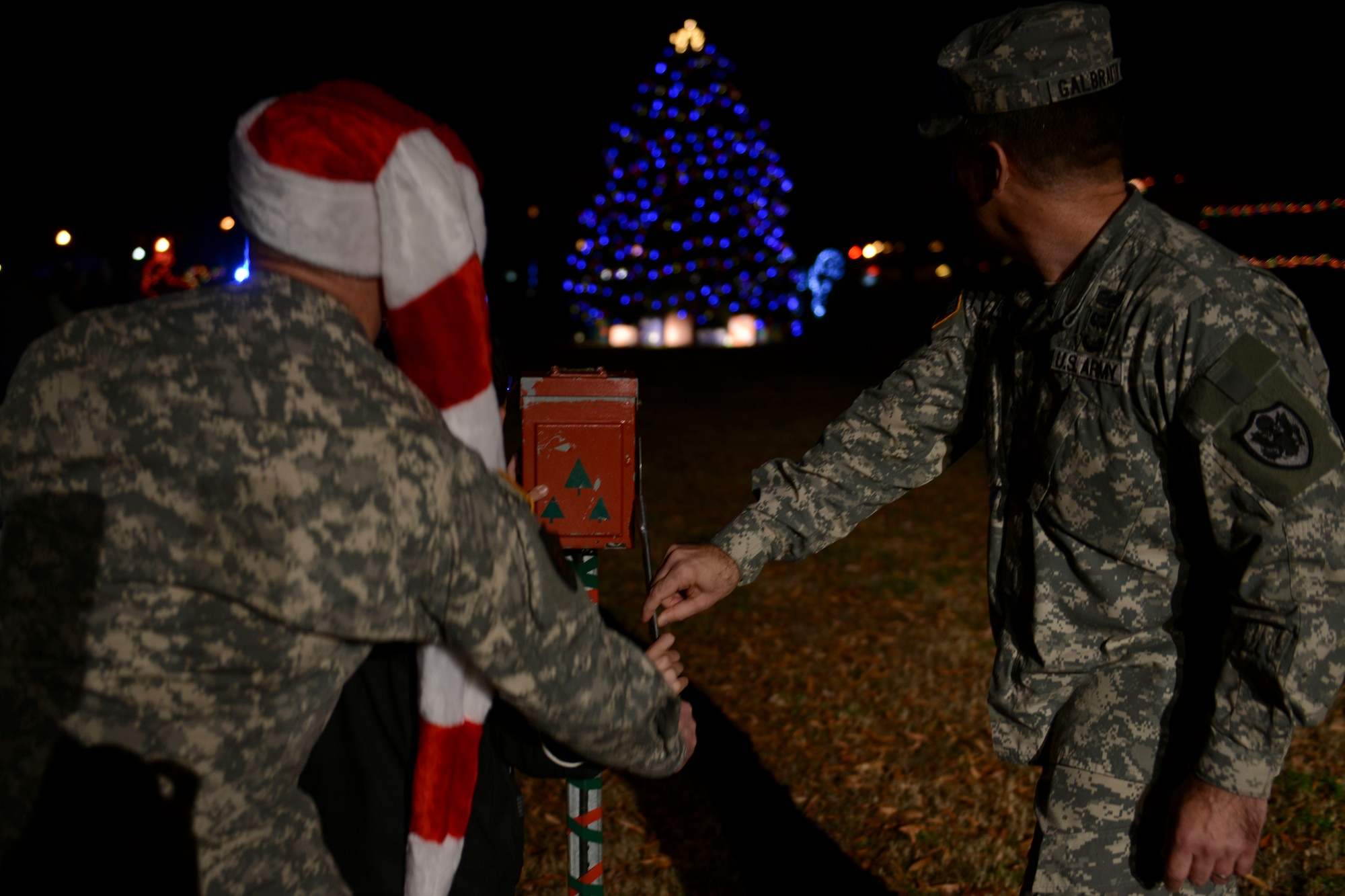 U.S. Army Maj. Gen. Ross Ridge, Initial Military Training commanding general, left, and Col. William Galbraith, 733rd Mission Support Group commander, right,  join Christopher York, 10, bottom left front, son of Spc. Brandon York, 690th Rapid Port Opening Element truck driver, to ceremonially light the Christmas tree at Fort Eustis, Va., Dec. 6, 2013. The 58th annual ceremony was held at Wylie Theater and Seay Plaza.  (U.S. Air Force photo by Staff Sgt. Ciara Wymbs/Released)
