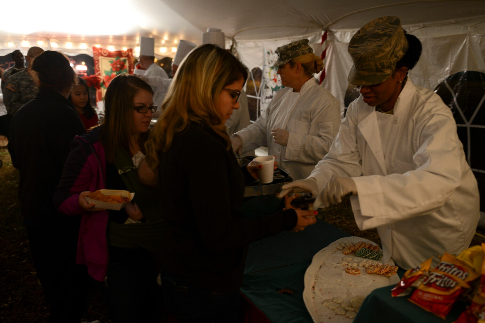 Joint Base Langley-Eustis leaders serve refreshments to attendees of the Christmas tree lighting ceremony at Fort Eustis, Va., Dec. 6, 2013. After the tree-lighting portion, families visited Santa Claus for photos and to make Christmas gift requests. (U.S. Air Force photo by Staff Sgt. Ciara Wymbs/Released)