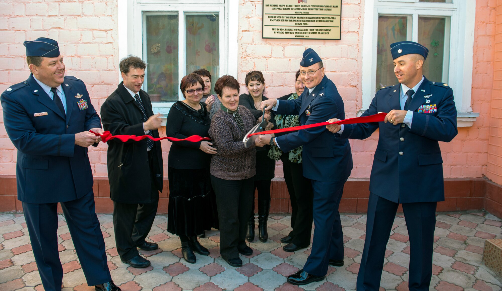 Local civic leaders and leadership from the Transit Center at Manas, join together to cut a ribbon after a dedication ceremony, signifying the completion of the newly renovated Leninskoe Village Kindergarten in Leninskoe, Kyrgyzstan, Dec. 6, 2013. The school principal hosted the ceremony, which included a trip through all of the renovated areas of the school. (U.S. Air Force photo/Staff Sgt. Travis Edwards)