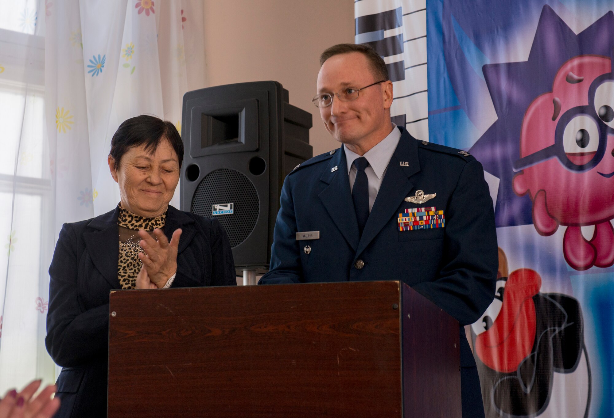 Col. John Vaughn, 376th Air Expeditionary Wing vice commander, concludes his speech during a roof-dedication ceremony as Valentina Turabekova, host-nation advisor to the 376th AEW commander, prepares to translate at the Leninskoe Village Kindergarten in Leninskoe, Kyrgyzstan, Dec. 6, 2013. The roof was fully renovated in less than a month and was the final touch in the complete overhaul of the school. Vaughn is deployed from Camp H.M. Smith, Hawaii, and a Granville, Ohio native.  (U.S. Air Force photo/Staff Sgt. Travis Edwards)