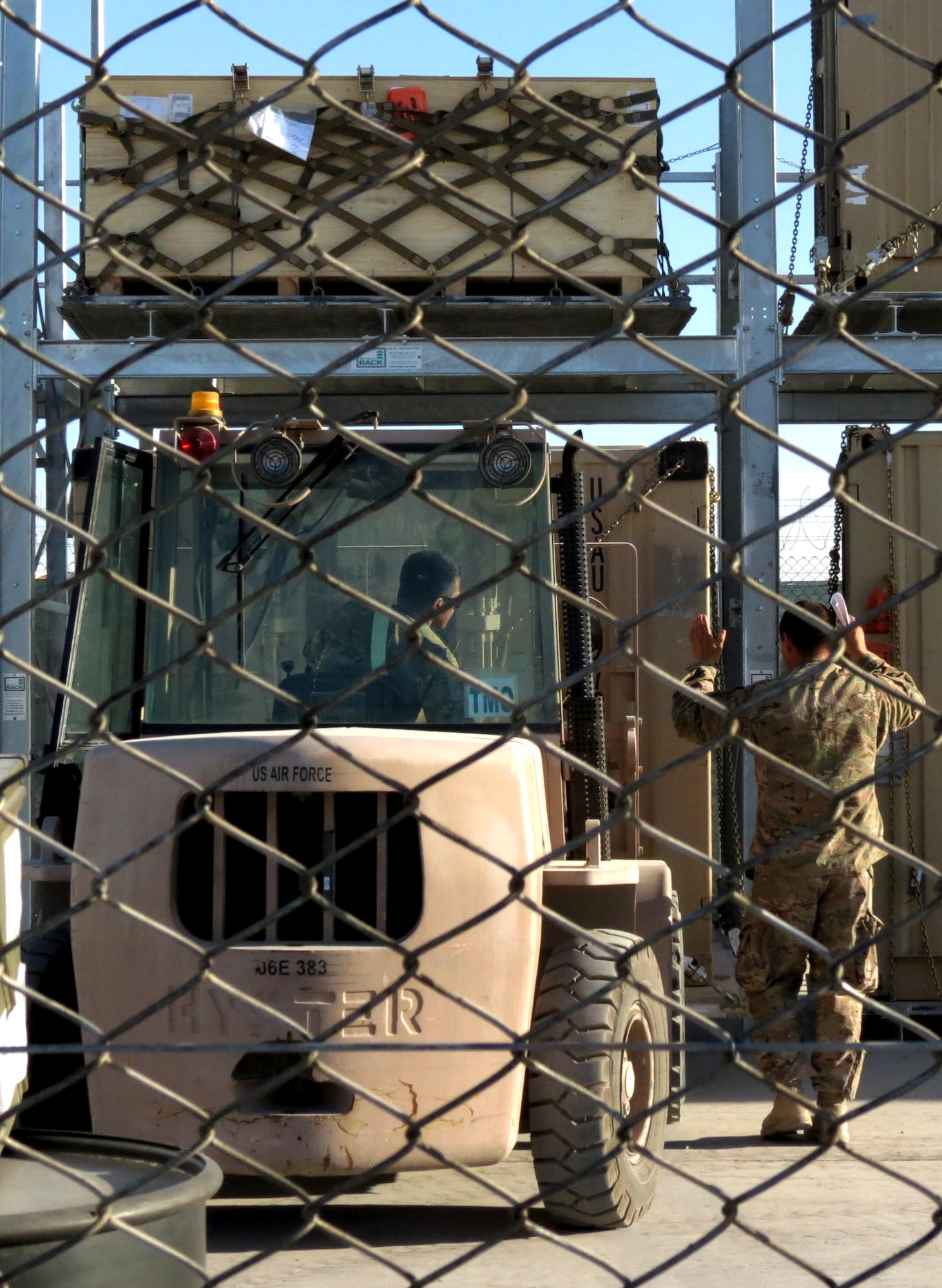Senior Airman Franciso Dionisio, 451st Expeditionary Logistic Readiness Squadron special handler, operates a forklift to load a pallet into the signature service surveillance yard while Tech. Sgt. Jesus Aguilar, 451 ELRS special handler, directs him Dec. 9, 2013, at Kandahar Airfield, Afghanistan. The signature surveillance yard is used to hold any cargo that requires continuous watch. (U.S. Air Force photo by Senior Airman Alexandria Bandin)