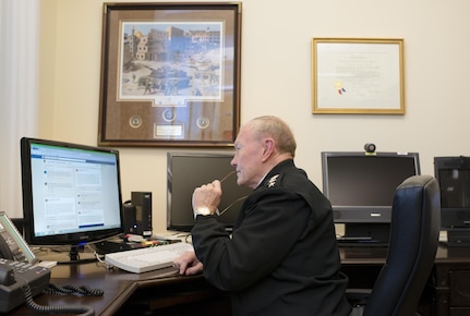 18th Chairman of the Joint Chiefs of Staff Gen. Martin E. Dempsey sits at his desk in the Pentagon and reads questions posted to his Facebook page during a Facebook Town Hall he hosted Dec. 5, 2013. This was the Chairman's first town hall utilizing social media as another way to receive feedback from the Joint Force.