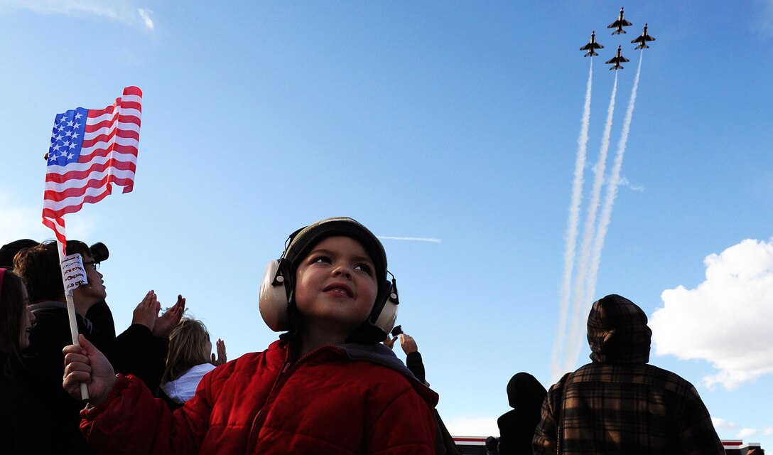 Three-year-old Mason Bain waves his U.S. flag as the U.S. Air Force Air Demonstration Squadron Thunderbirds, fly in the diamond formation Nov. 10, 2012, during an Aviation Nation airshow at Nellis Air Force Base, Nev. The Thunderbirds are the premier precision-flying demonstration team that flies red, white and blue F-16 Fighting Falcons. (U.S. Air Force photo/Staff Sgt. Larry E. Reid Jr.)
