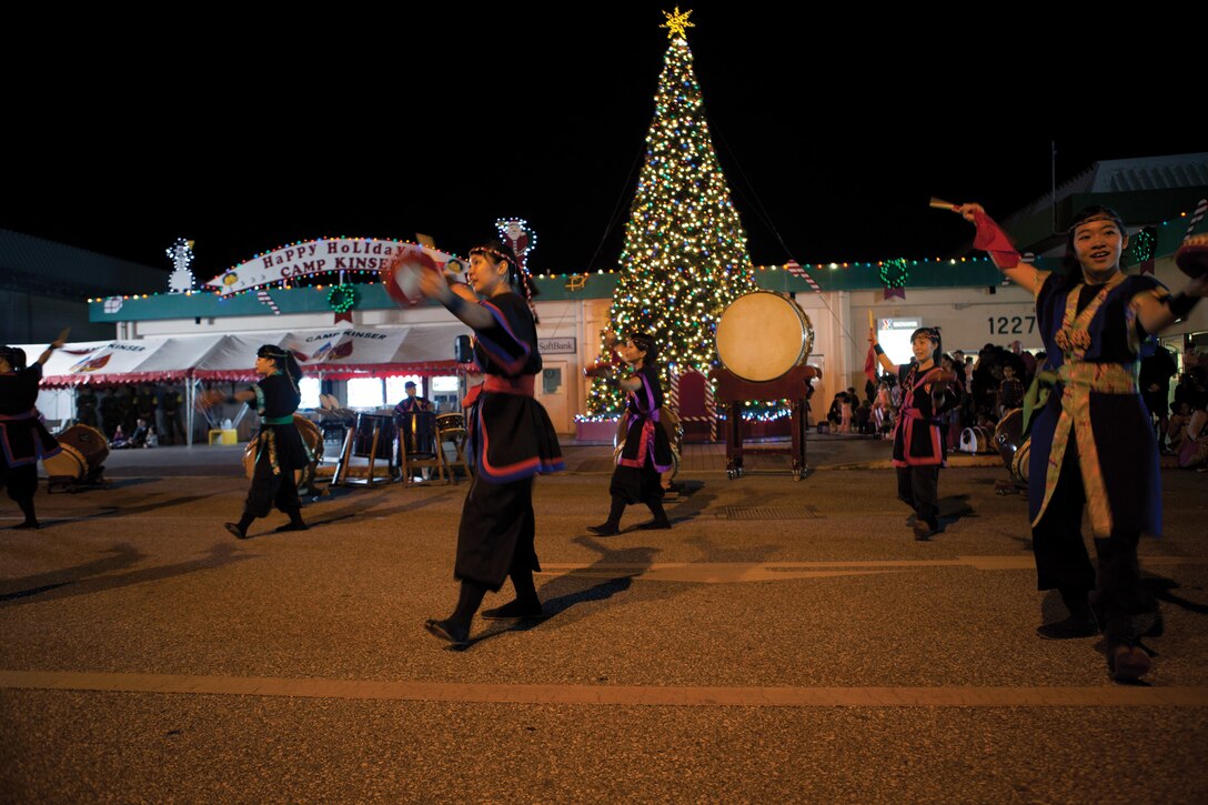 Service members, their families and communnity members celebrate the 7th annual holiday tree lighting Dec. 6 at the Camp Kinser Main Exchange. “Tonight (was) special,” said Col. Edmund J. Bowen. “This tree lighting ceremony represents a lot of things, no matter what religion, faith, whatever you believe in. That tree represents peace, love, good will to everyone and a great holiday.” Bowen is the Camp Kinser commander and commanding officer of Combat Logistics Regiment 37, 3rd Marine Logistics Group, III Marine Expeditionary Force. (U.S. Marine Corps photo by Lance Cpl. Diamond N. Peden/Released)