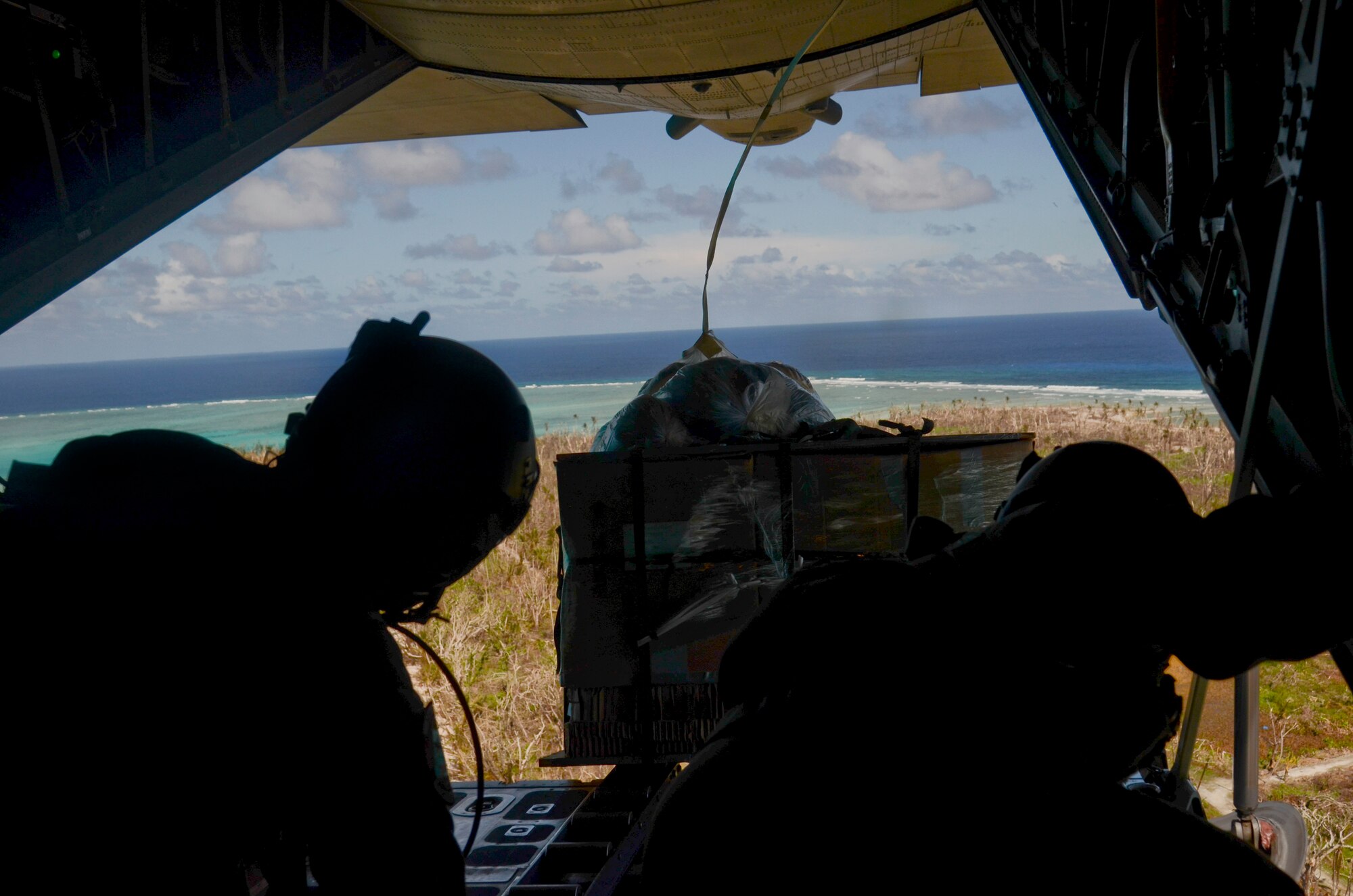 Loadmasters from the 36th Airlift Squadron from Yokota Air Base Japan push a package off the ramp of a C-130 Hercules during an Operation Christmas Drop mission over the islands of Micronesia Dec. 11, 2013. This year marks the 62nd year of Operation Christmas Drop, which began in 1952, making it the world's longest running airdrop mission. (U.S. Air Force photo by Senior Airman Marianique Santos/Released)