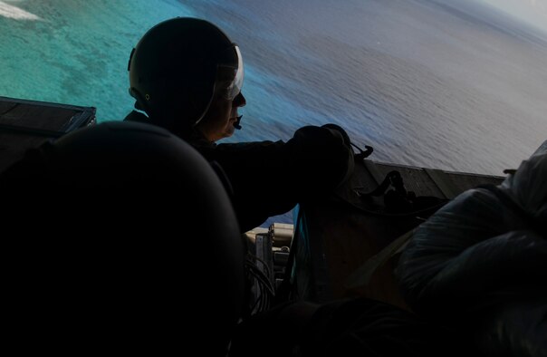 Chief Master Sgt. Reynold Albright, 36th Airlift Squadron loadmaster and chief enlisted manager from Yokota Air Base, Japan, holds on to packages during an Operation Christmas Drop mission over the Pacific Ocean Dec. 11, 2013. Every December, C-130 Hercules aircrews from the 374th Airlift Wing at Yokota AB partner with the 36th Wing at Andersen Air Force Base, Guam, to airlift food, supplies and toys to islanders throughout Micronesia. (U.S. Air Force photo by Senior Airman Marianique Santos/Released)