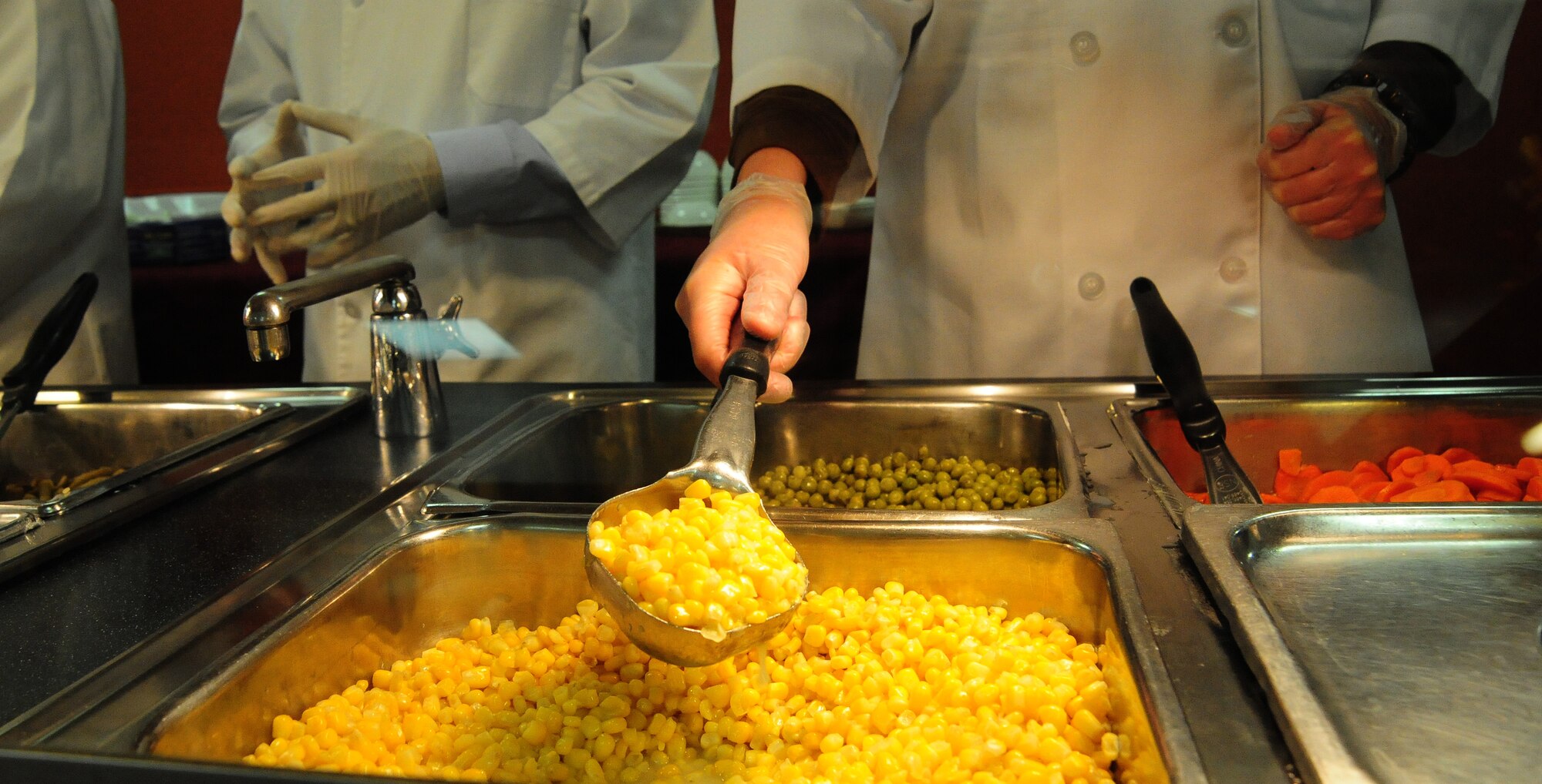 A volunteer stirs corn during a Thanksgiving luncheon at the Ozark Inn on Whiteman Air Force Base, Mo., Nov. 28, 2013. The event was put on to boost morale for Airmen that are working through the holidays and can’t make it home to their families. (U.S. Air Force photo by Staff Sgt. Nick Wilson/Released)