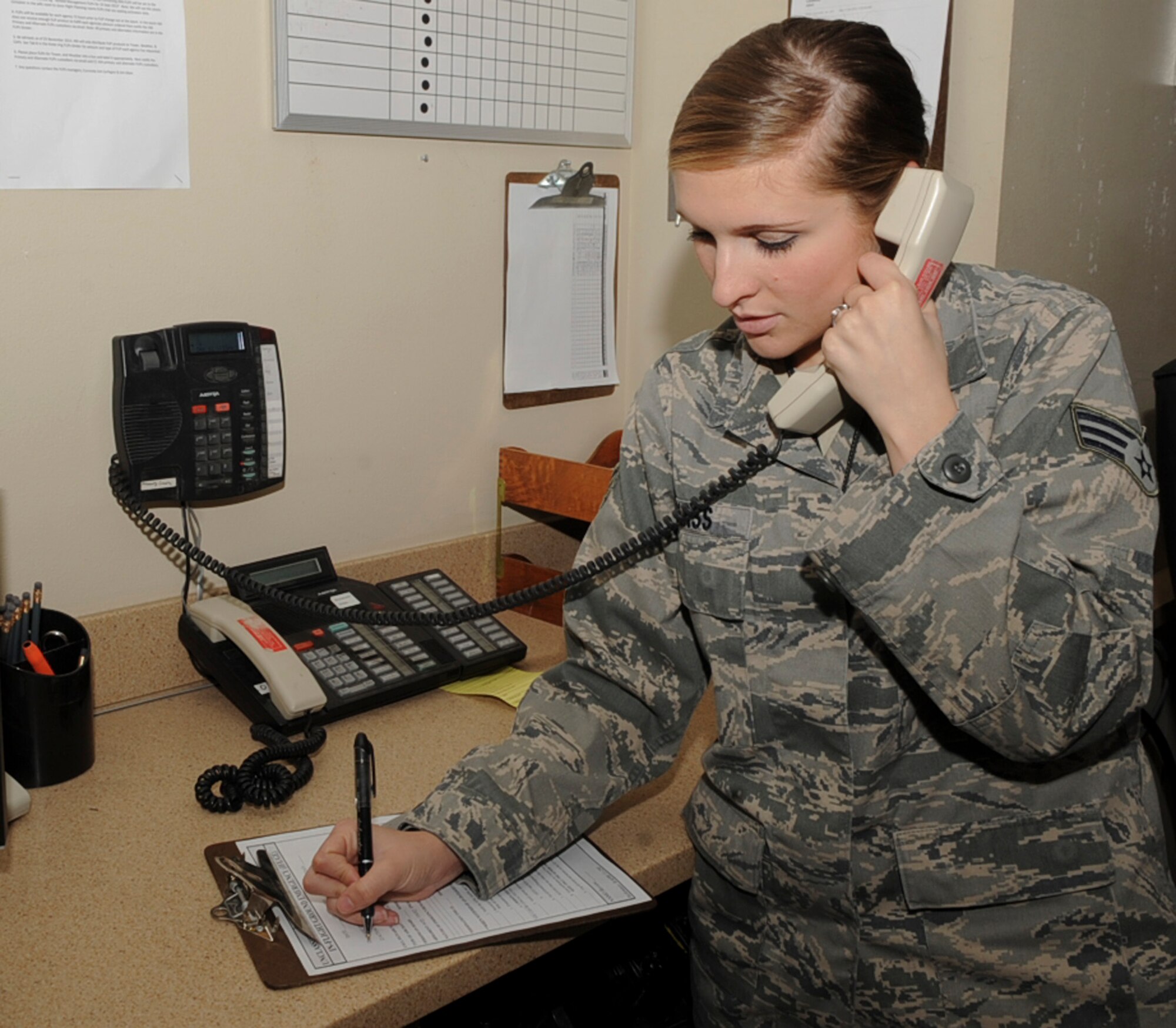 Senior Airman Meghan Glass, 2nd Operations Support Squadron airfield management, adjusts a flight plan as she talks to an Airman in the control tower on Barksdale Air Force Base, La., Dec. 11, 2013. Airfield management Airmen are responsible for the overall management of AM facilities and services to provide a safe, efficient and effective airfield environment for aircraft operations. (U.S. Air Force photo/Senior Airman Kristin High)
