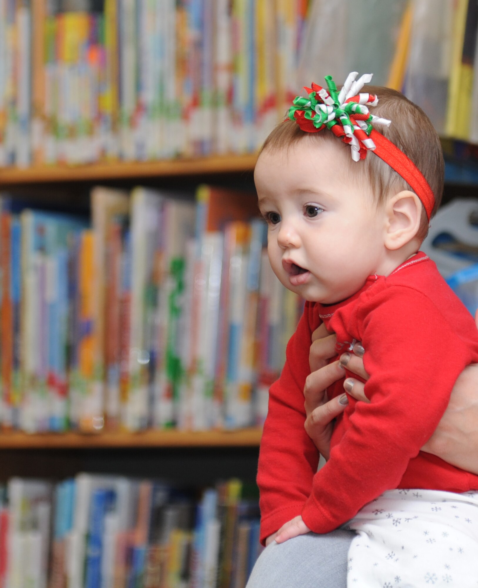 The daughter of Capt. Jesse Payne, 81st Medical Operations Squadron, looks on as the “Dream Snow” is read to Keesler children during the Library open house story time session Dec. 11, 2013, at Keesler Air Force Base, Miss.  The book “Twas The Night Before Christmas” was also read to the children and they did arts and crafts afterwards.  (U.S. Air Force photo by Kemberly Groue)