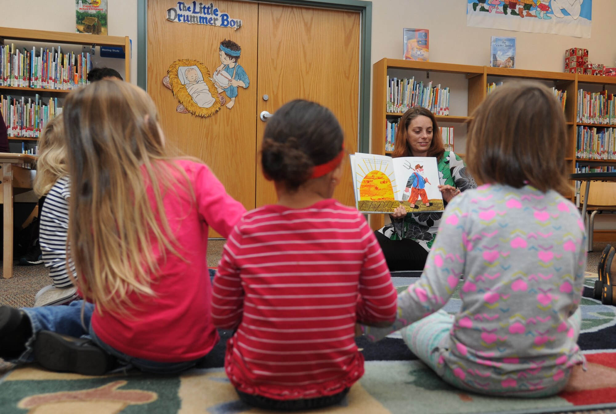 Kate Baughman, McBride Library contractor, reads “Dream Snow” to Keesler children during the Library open house story time session Dec. 11, 2013, at Keesler Air Force Base, Miss.  Baughman also read “Twas The Night Before Christmas” and did arts and crafts with the children.  (U.S. Air Force photo by Kemberly Groue)