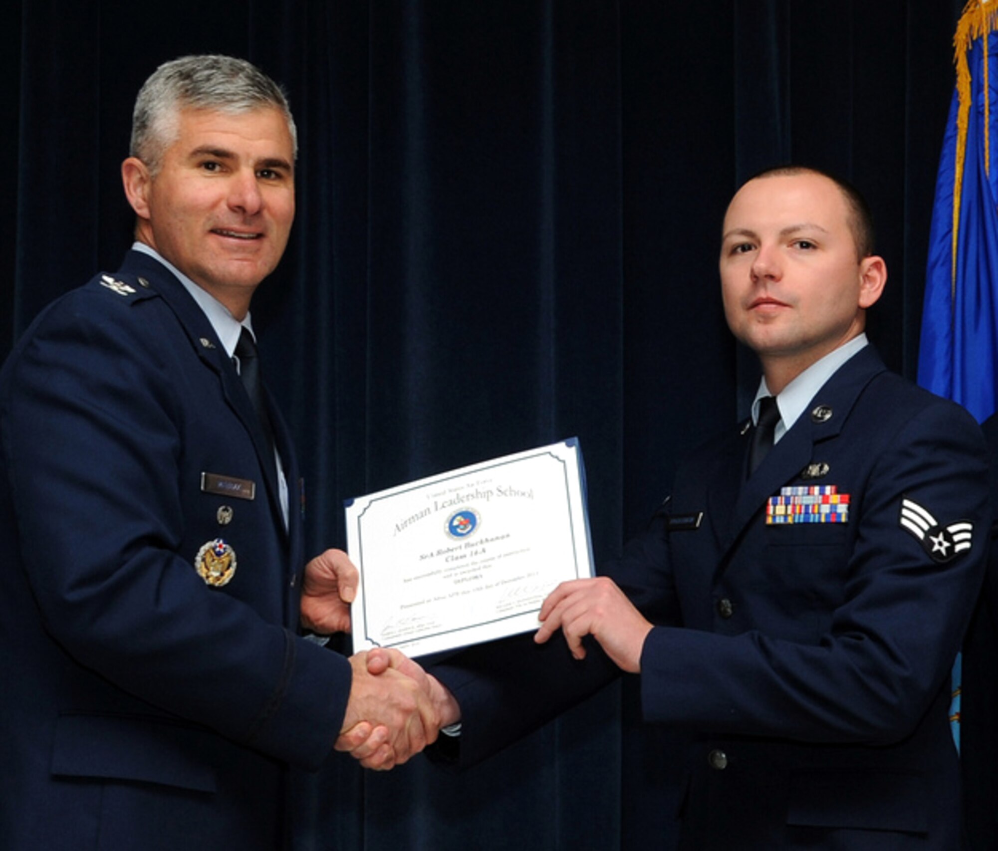 Senior Airman Robert Buckhanan, right, receives his Airman Leadership School certificate from Col. John Menozzi during the Class 14-A graduation ceremony held Dec. 10 at Altus Air Force Base, Okla. Buckhanan, with the 71st Operations Support Squadron at Vance Air Force Base, Okla., also received the Commandant’s Award. Menozzi is the 71st Flying Training Wing vice commander at Vance AFB. (U.S. Air Force photo/ Senior Airman Franklin Ramos)