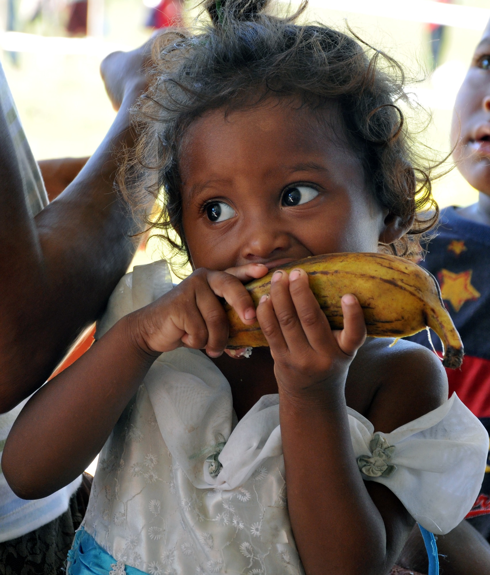 A young Honduran child enjoys a banana while waiting to see a doctor during a Medical Readiness Training Exercise (MEDRETE) conducted by Joint Task Force-Bravo in the Department of Gracias a Dios, Honduras, Dec. 4, 2013.  Joint Task Force-Bravo routinely partners with the Honduran Ministry of Health and the Honduran military to perform these humanitarian aid missions to provide medical care to the most isolated regions of the country. (U.S. Air Force photo by Capt. Zach Anderson)