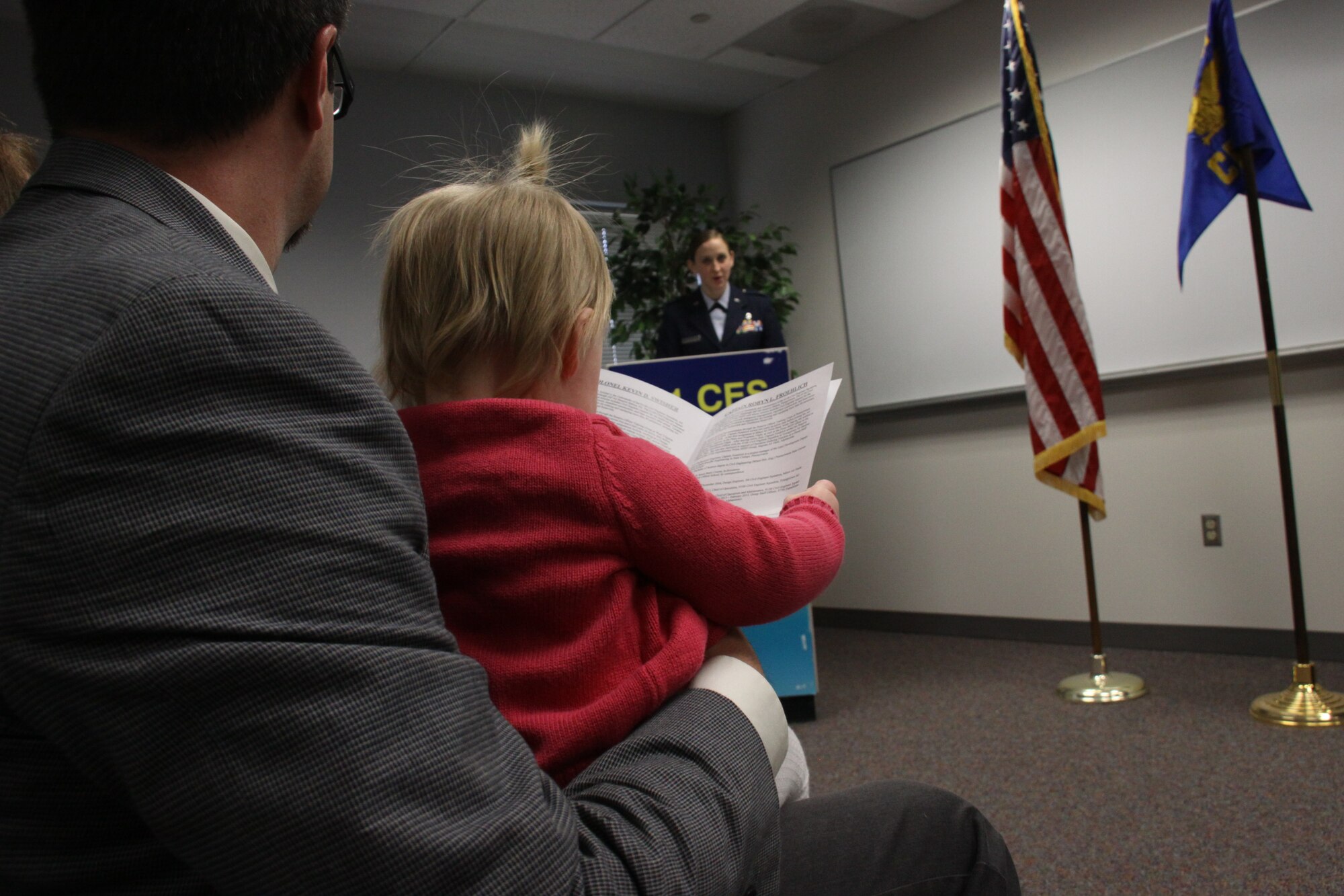 Dakota Froehlich, daughter of Capt. Robyn Froehlich, reviews the program during her mother’s change of command ceremony at the Pittsburgh International Airport Air Reserve Station, Dec. 8th, 2013. Froehlich assumed command of the 911th Airlift Wing Civil Engineering Squadron from Lt. Colonel Kevin Swisher in front of numerous family members, Airmen, and Commanders. (U.S. Air Force photo by Senior Airman Justyne Obeldobel)