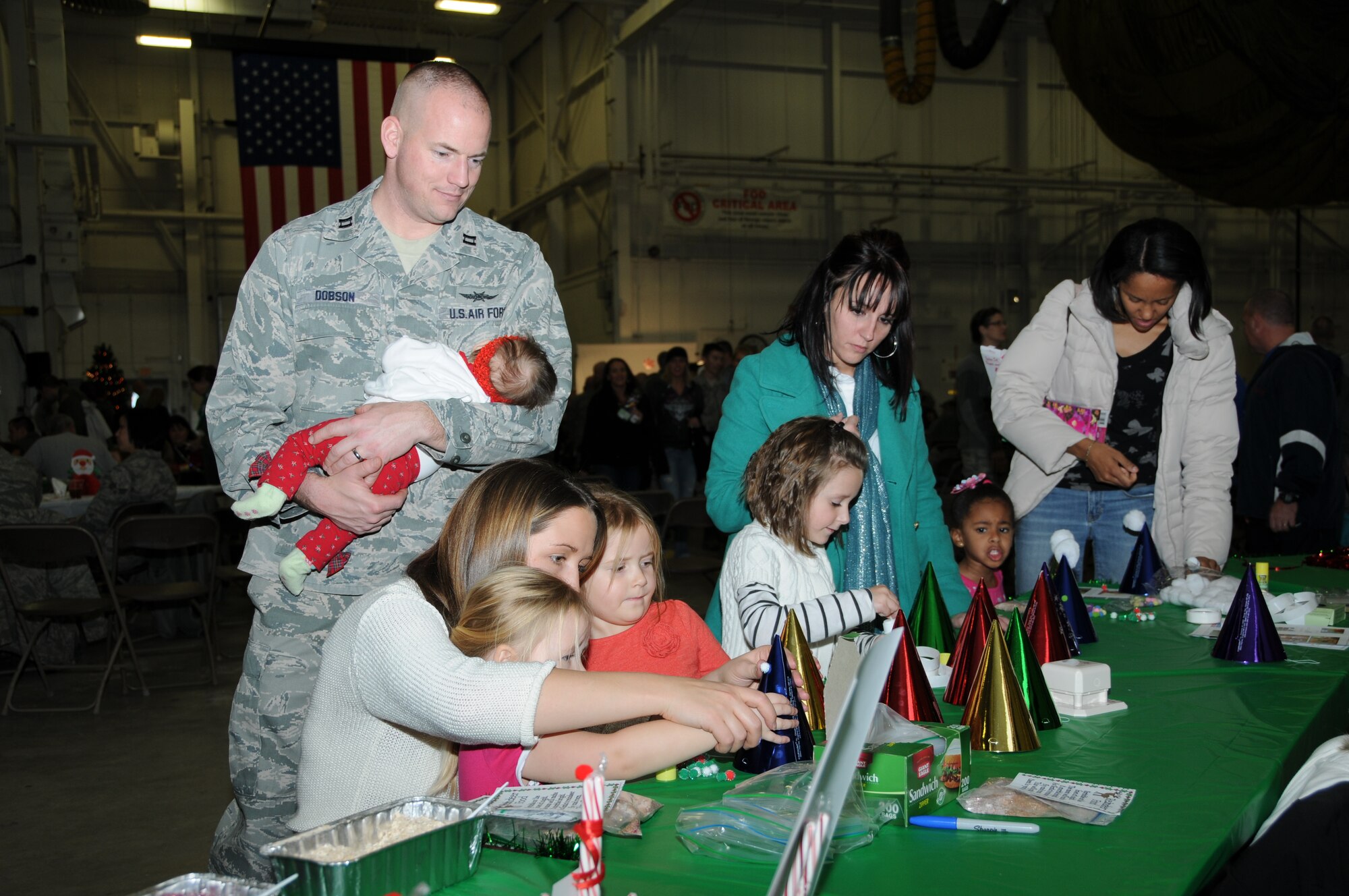 Capt. Geoffrey Dobson, 911th Communications Squadron director of communications, watches as his wife and kids put together festive holiday hats of joy, at the 911th Airlift Wing holiday party at the Pittsburgh International Airport Air Reserve Station, Dec. 7, 2013. (U.S. Air Force photo by Senior Airman Joshua J. Seybert)