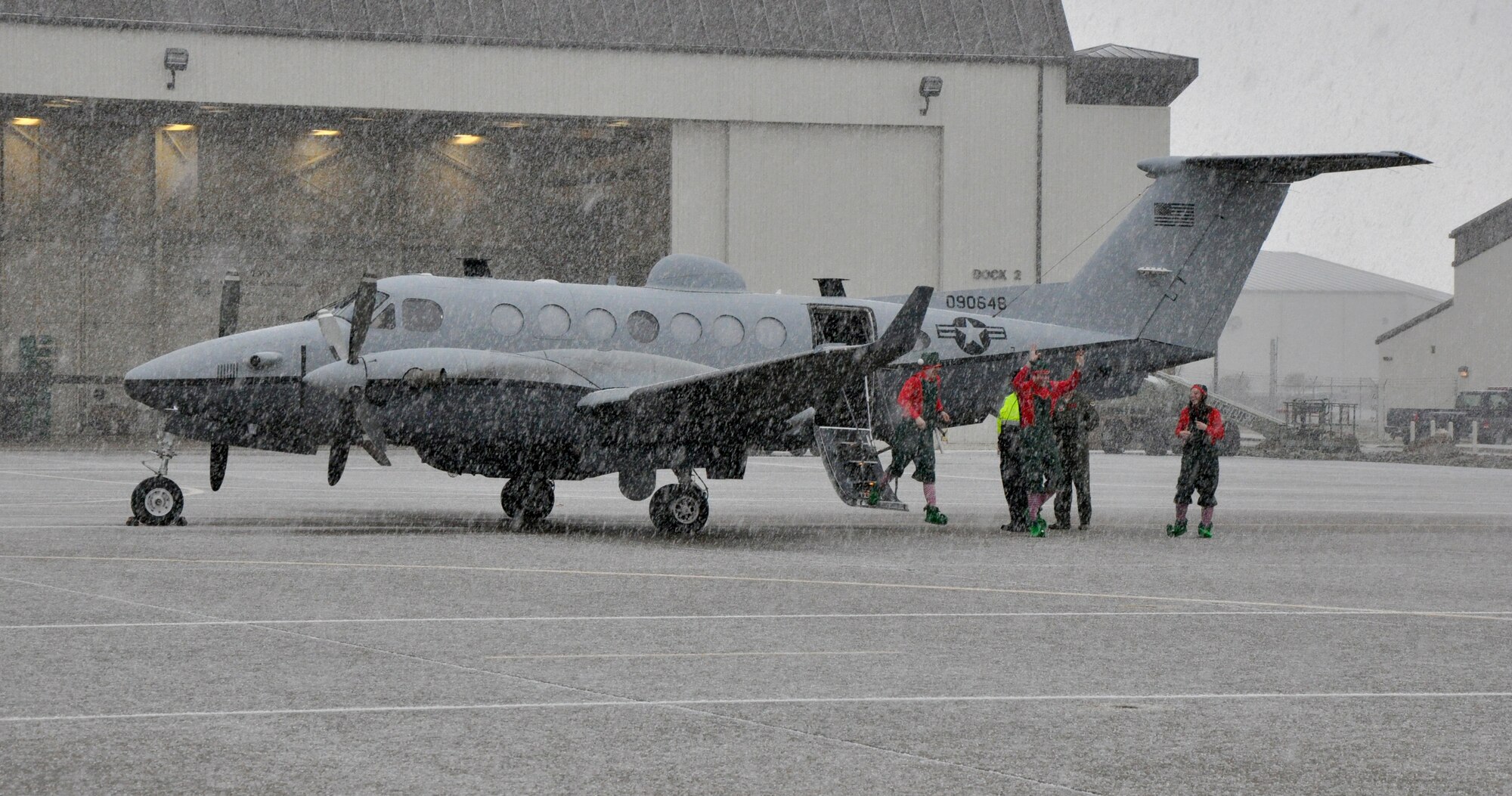 Santa’s helpers exit a MC-12 Liberty aircraft during Beale’s annual Children’s Holiday Party at Dock 6 Dec. 7, 2013.The special visitors arrived amidst a rare snowfall. (U.S. Air Force photo by Staff Sgt. Robert M. Trujillo/Released)