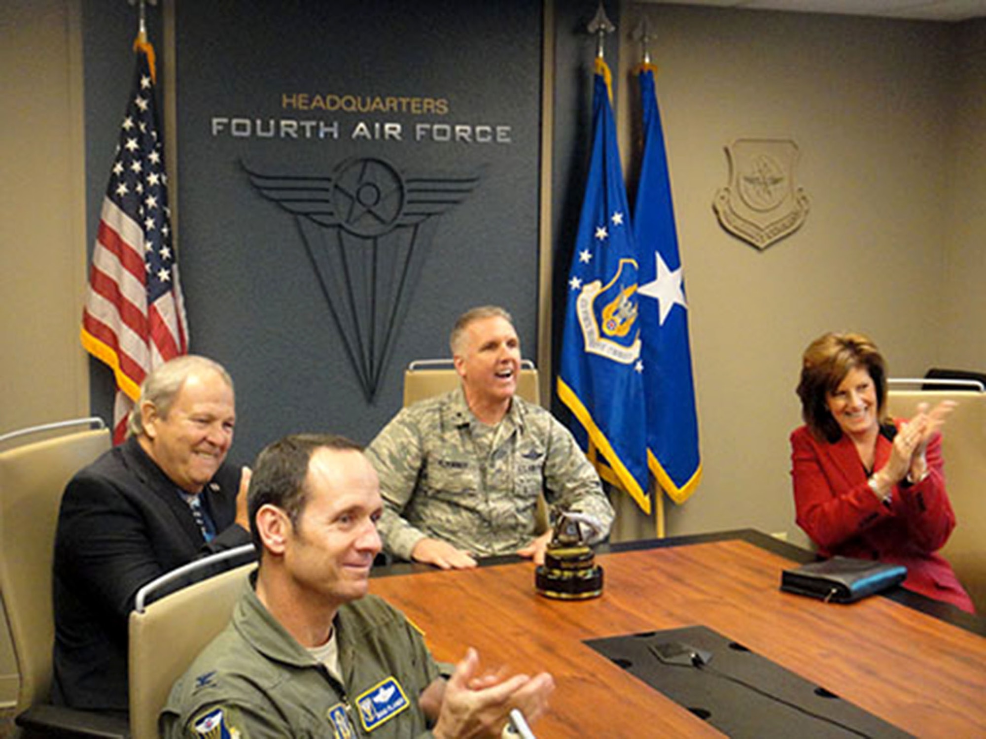 MARCH AIR RESERVE BASE, Calif. -- Col. Douglas Planer (foreground), 4th Air Force A3 Director, joins (from left) Roger Rupp, Riverside Military Affairs Committee Chairman; Brig. Gen. John C. Flournoy Jr., 4th Air Force Commander; and Cindy Roth, Greater Riverside Chambers of Commerce President, in congratulating the 349th Air Mobility Wing, Travis Air Force Base, Calif., for being named the best wing in 4th Air Force for 2012 and 2013 combined. Flournoy surprised the wing’s senior leadership with the announcement via teleconference on Friday, Dec. 6, 2013. (Courtesy photo)