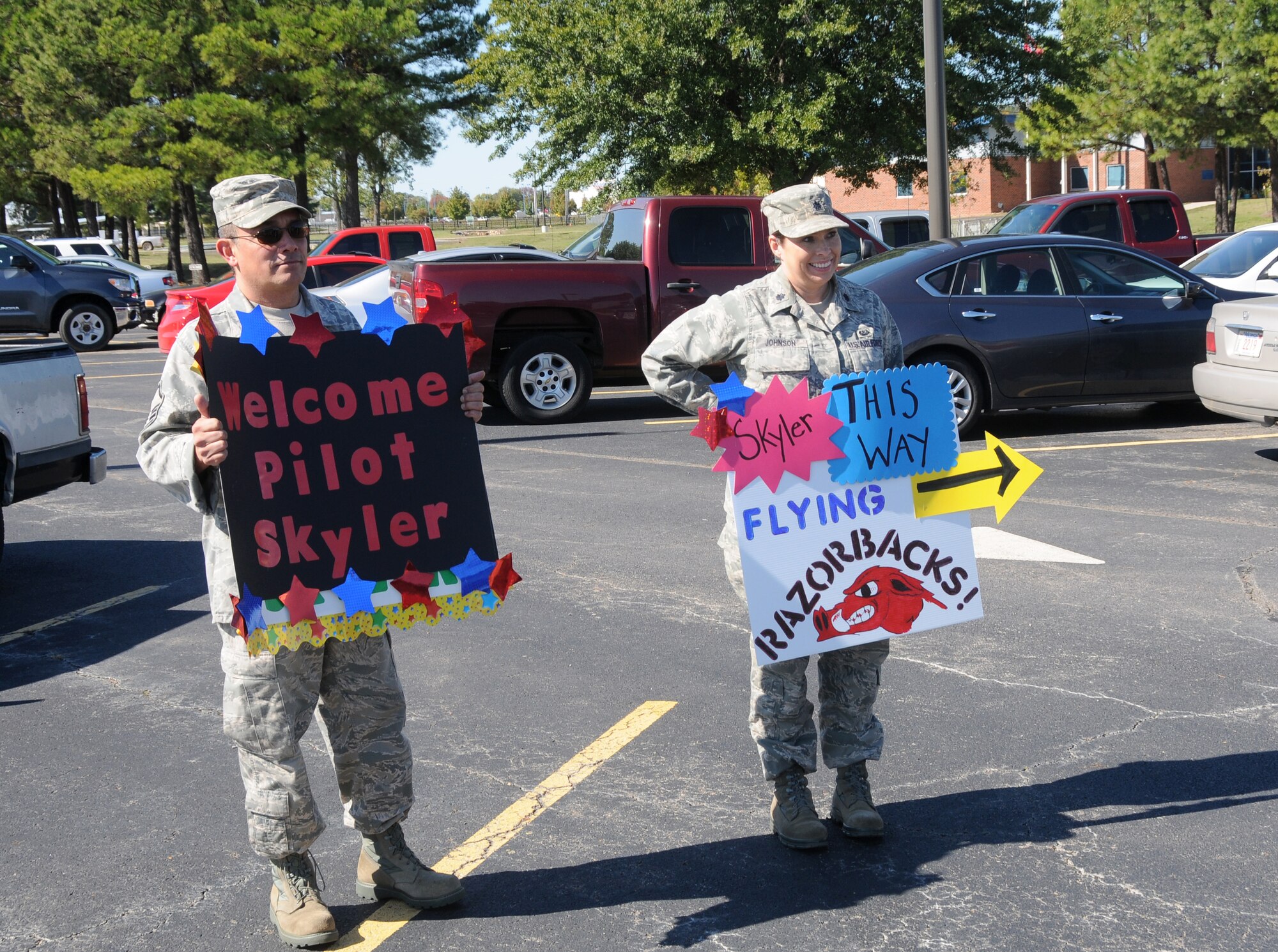 Master Sgt. Jesse Cabalar, a knowledge operations management specialist with the 188th Mission Support Group, and Lt. Col. Jenny Johnson, 188th Fighter Wing judge advocate, hold signs welcoming pilot for a day Skyler Leroy to the 188th. (U.S. Air National Guard photo by Senior Airman John Hillier/188th Fighter Wing Public Affairs)