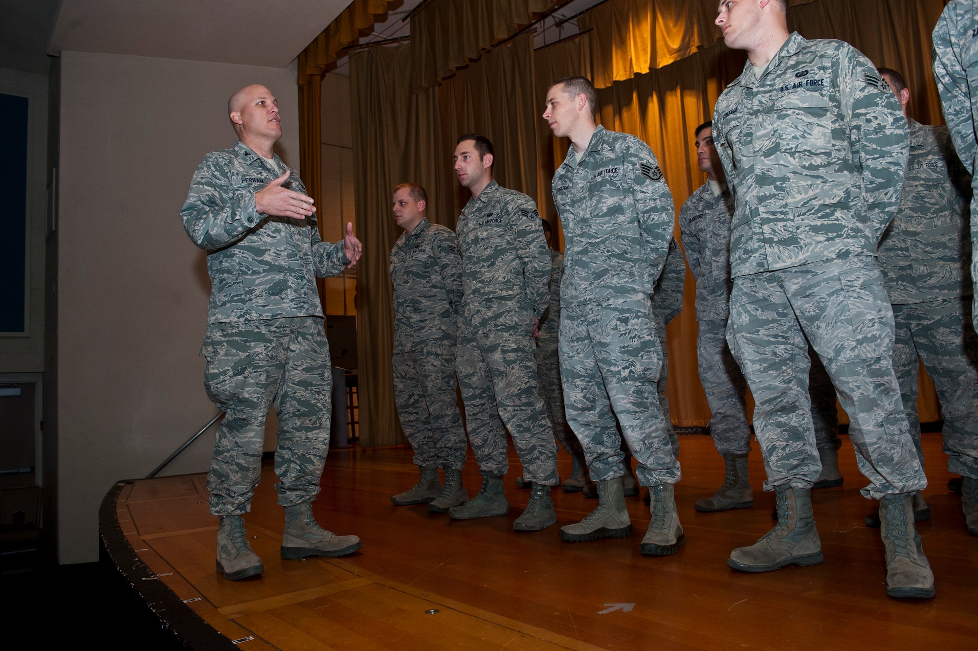 U.S. Air Force Col. Charles Perham, 99th Mission Support Group commander, talks to Airmen at a reenlistment ceremony Dec. 4, 2013, inside the base theater at Nellis Air Force Base, Nev. Forty-six career fields eligible for reenlistment bonuses, and the USAF reduced the list to 10 Air Force Specialty Codes. (U.S. Air Force photo/Senior Airman Brett Clashman)