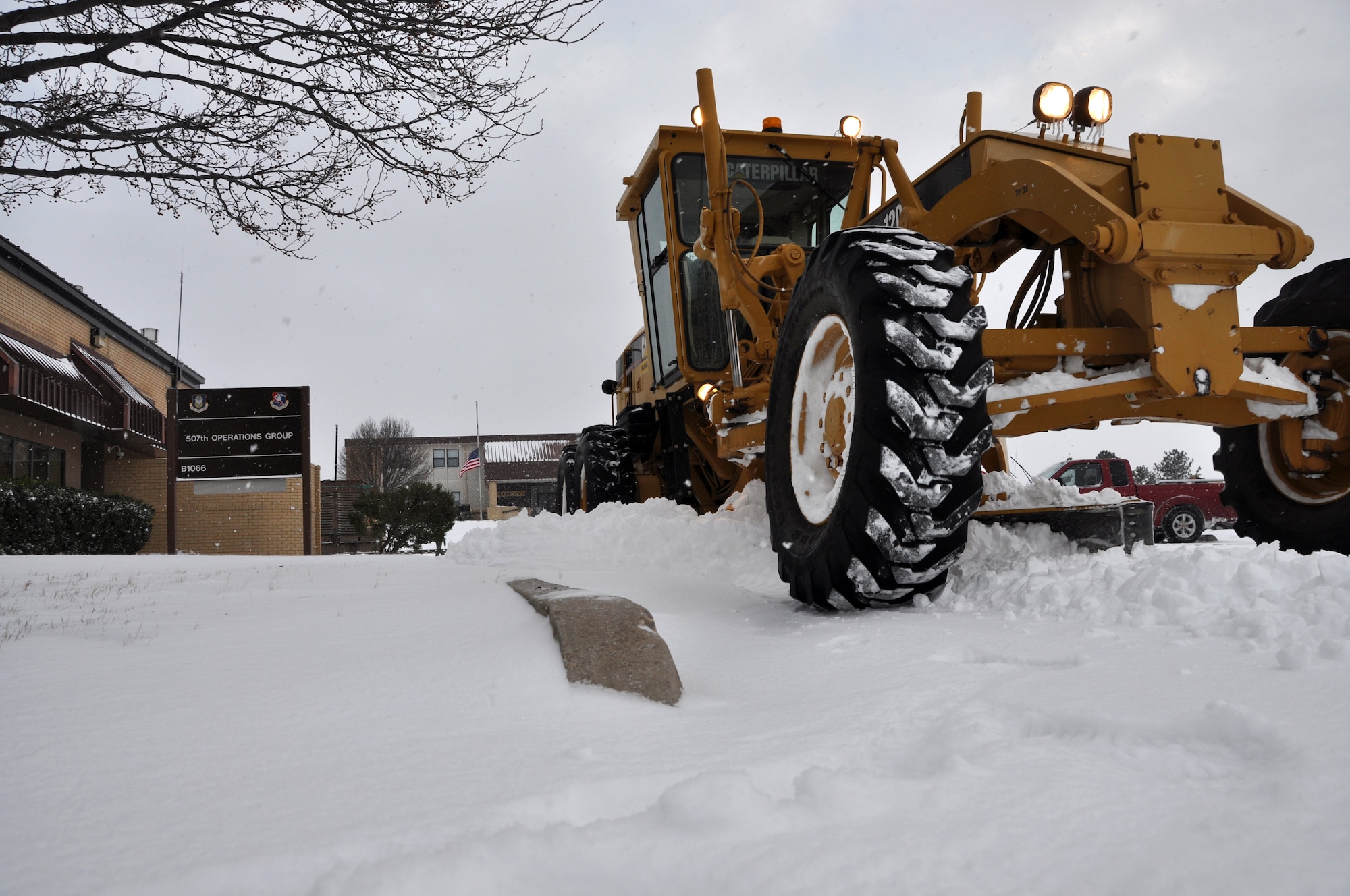 A  Caterpillar grader takes time to plow the 507th Operations Group parking lot.  The giant plow made its way to the flight line to clear the snow away from the KC-135R Stratotankers.  No flight operations were conducted Friday Dec. 6, 2013 as a massive snow and ice storm that spanned several states moved through the area.  All schools and state facilities were closed Friday due to the weather however, Airmen at the 507th braved the elements in preparation for the Unit Training Assembly.  (U.S. Air Force photo/Senior Airman Mark Hybers)