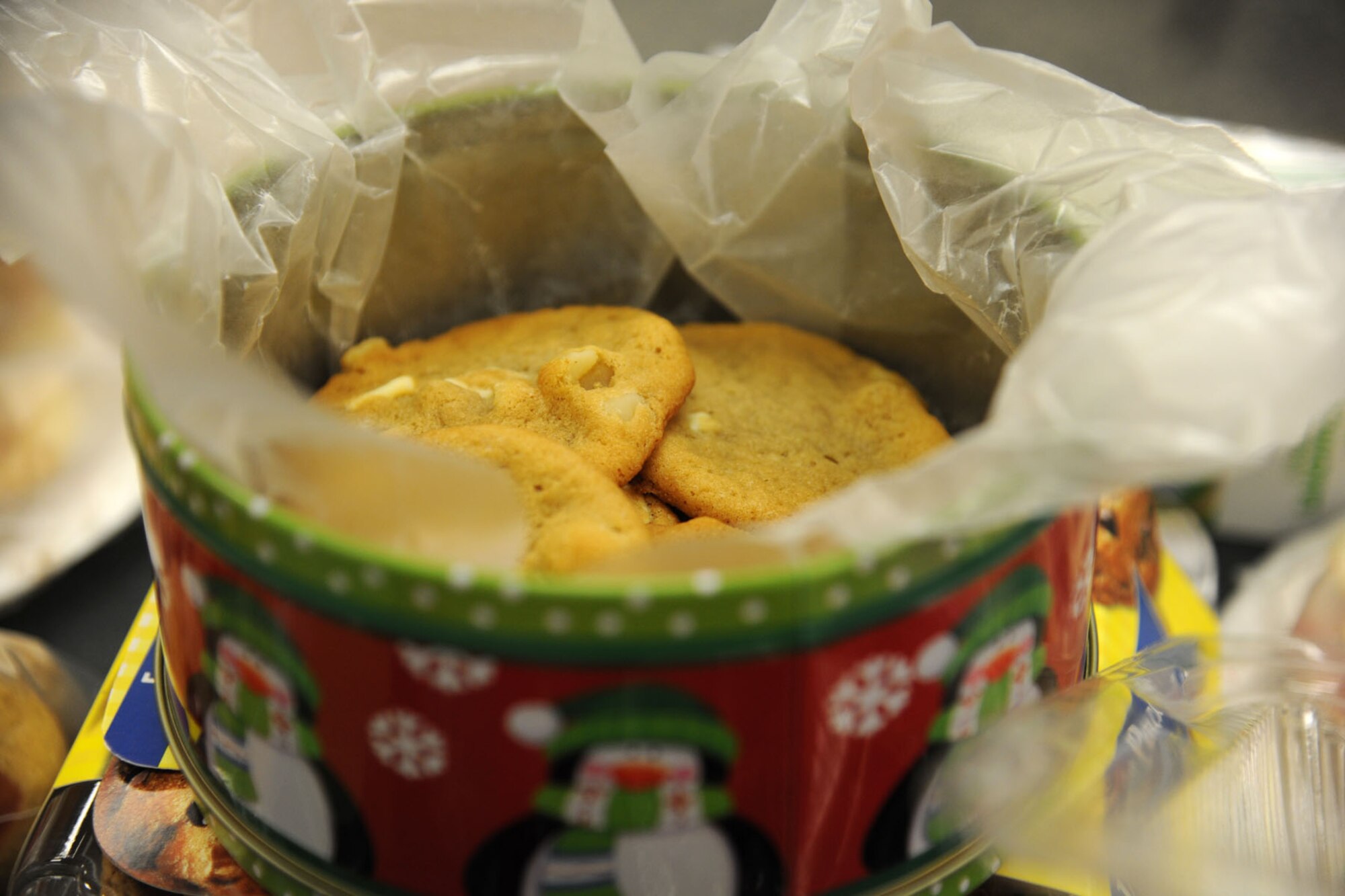 PETERSON AIR FORCE BASE, Colo. – A tin filled with white chocolate macadamia nut cookies await to be bundled and distributed to the Airmen of Peterson Air Force Base. These cookies are just a few of the more than 6,000 cookies donated as part of the Cookies for the Troops drive led by the Peterson, Schriever, Cheyenne Mountain Spouses’ Club. Members of the PSC Spouses’ Club volunteered their time, using the baked goods to spread homemade, holiday cheer to the more than 400 Airmen residing in the Team Pete dorms and also to the 30 on-base squadrons running 24-hour operations. (U.S. Air Force Photo/Staff Sgt. J. Aaron Breeden)