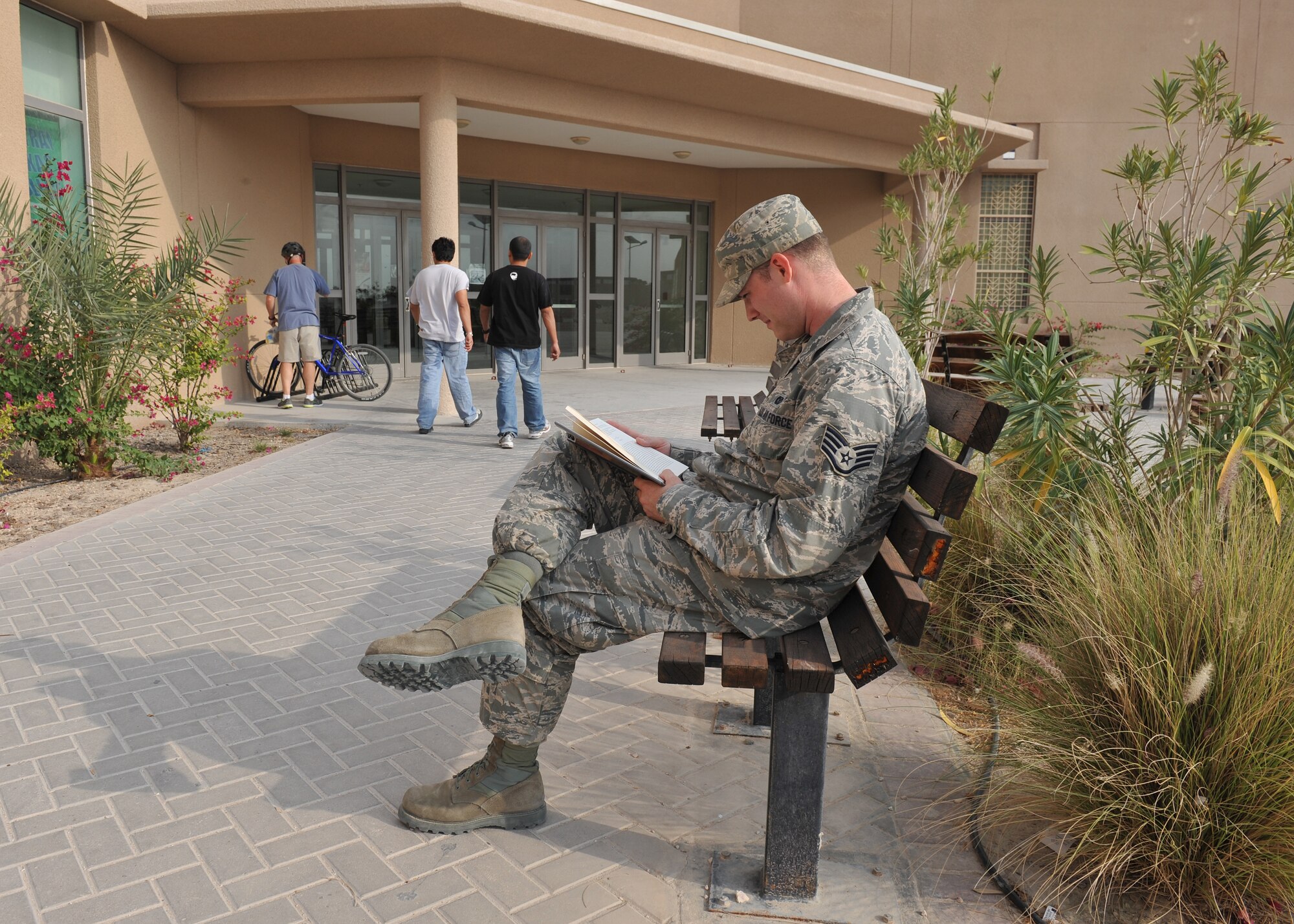 Staff Sgt. Dustin Roberts, 379th Air Expeditionary Wing Public Affairs broadcast journalist, reads a book outside the Blatchford-Preston Complex mall. The benches outside of the BPC mall were renovated by members of the First Four organization. With the support of 46 volunteers, 16 benches were refurbished over a three day period. The mission of the First Four is to improve morale, provide welfare, and inspire growth for all individuals assigned here. Roberts is deployed from Andersen Air Force Base, Guam and a Tifton, Ga., native. (U.S. Air Force photo/Master Sgt. David Miller)