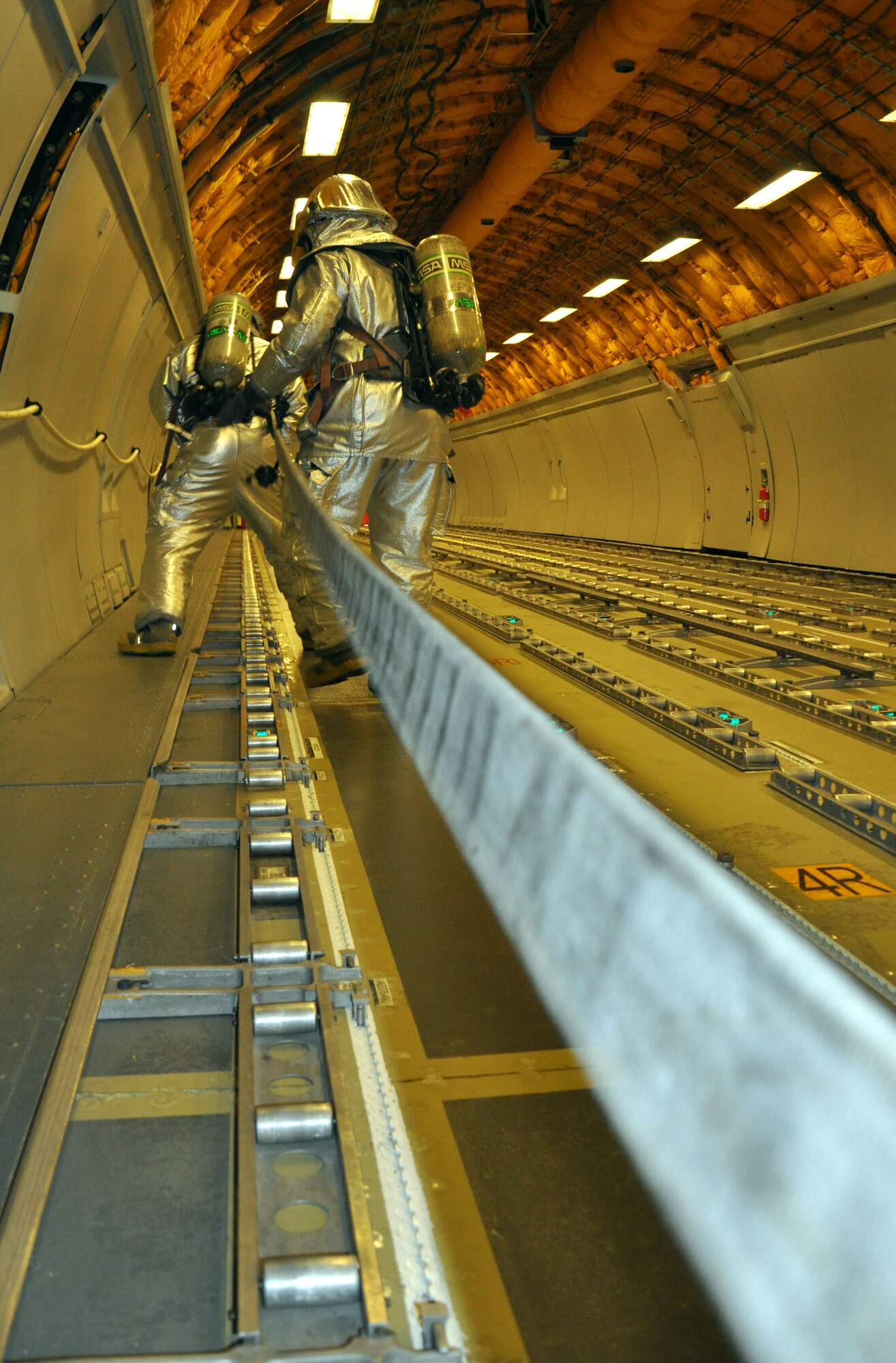 Firefighters, who are assigned to the 380th Expeditionary Civil Engineer Squadron here, advance their attack line to fight simulated fire and search for victims during a training scenario aboard a KC-10 Extender Dec. 10, 2013. (U.S. Air Force photo by Master Sgt. April Lapetoda/Released) 