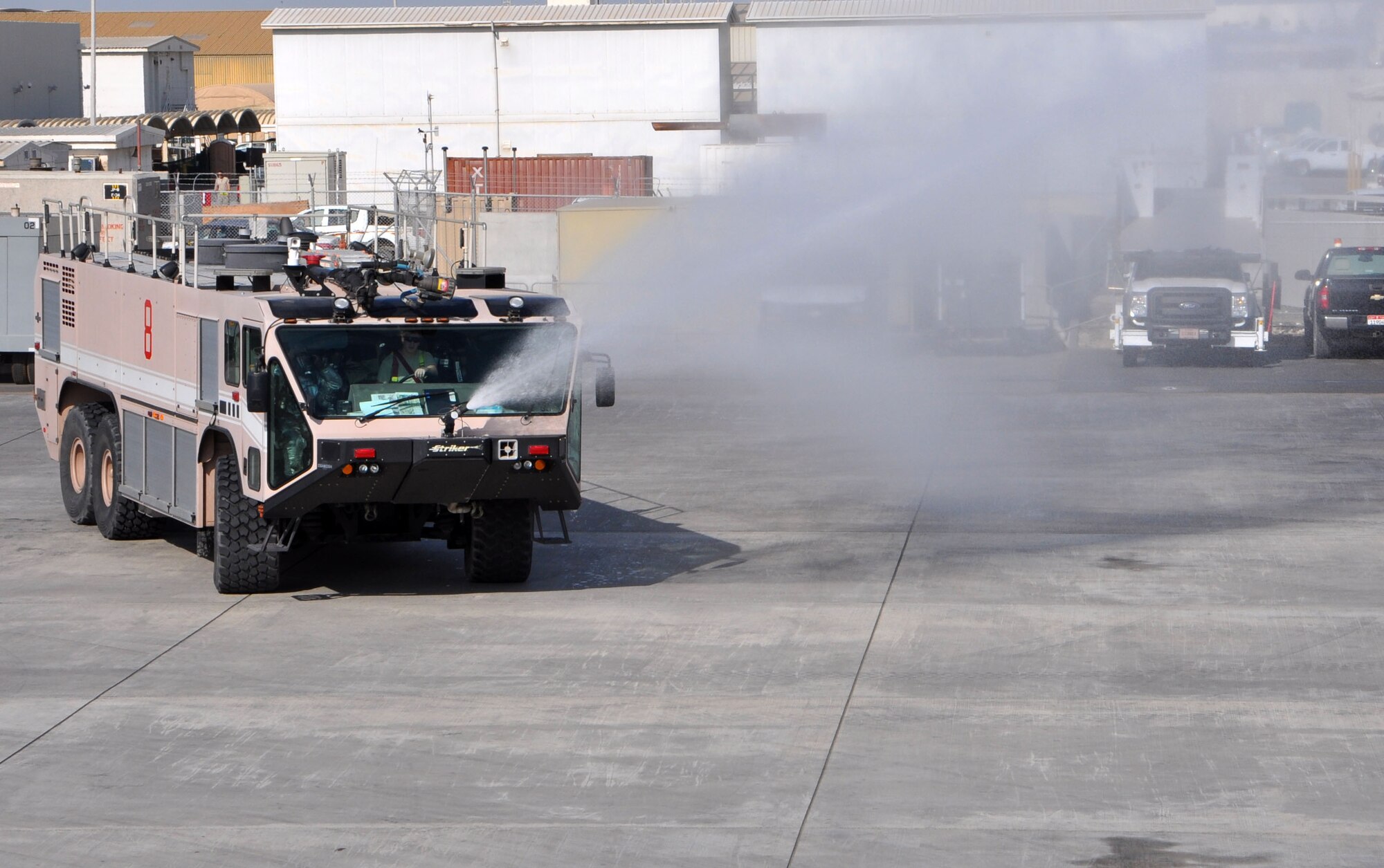 An Aircraft Rescue Fire Fighting truck sprays water near a KC-10 Extender on the 380th Air Expeditionary Wing’s flightline Dec. 10, 2013. Firefighters sprayed near the aircraft instead of  on the actual aircraft as this was part of a training scenario. (U.S. Air Force photo by Master Sgt. April Lapetoda/Released)