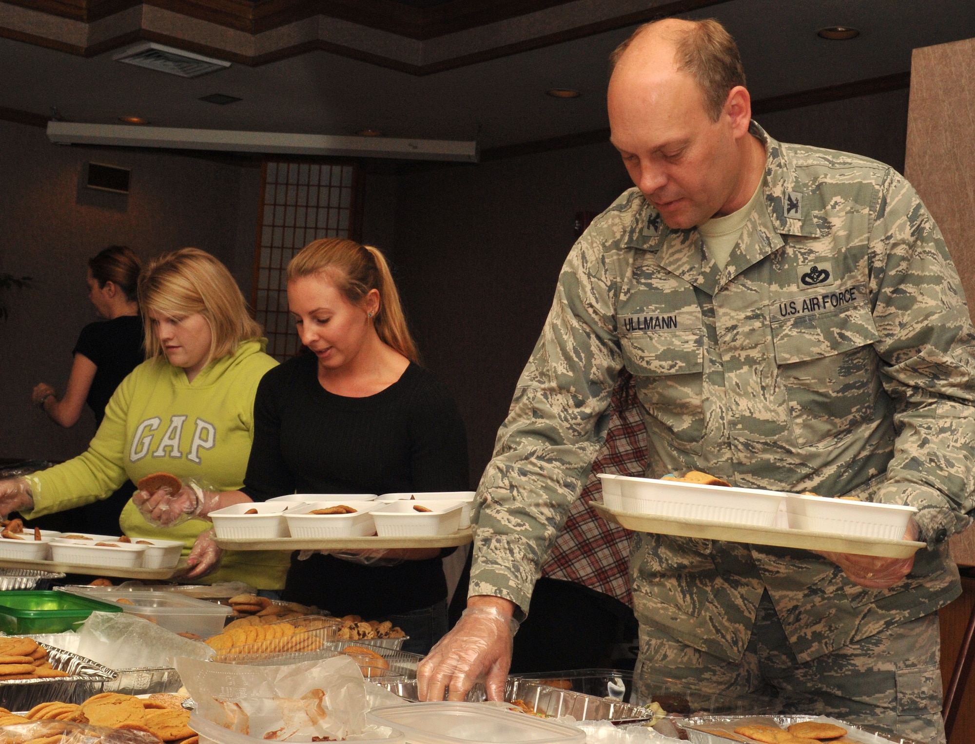U.S. Air Force Col. Jeffrey Ullmann, 18th Mission Support Group commander, helps transfer cookies into trays during the 2013 Team Kadena Cookie Drive on Kadena Air Base, Japan, Dec. 11, 2013. These handmade cookies were distributed to single, dorm residing Airmen, Sailors, Soldiers and Marines living on Kadena. (U.S. Air Force photo by Naoto Anazawa)