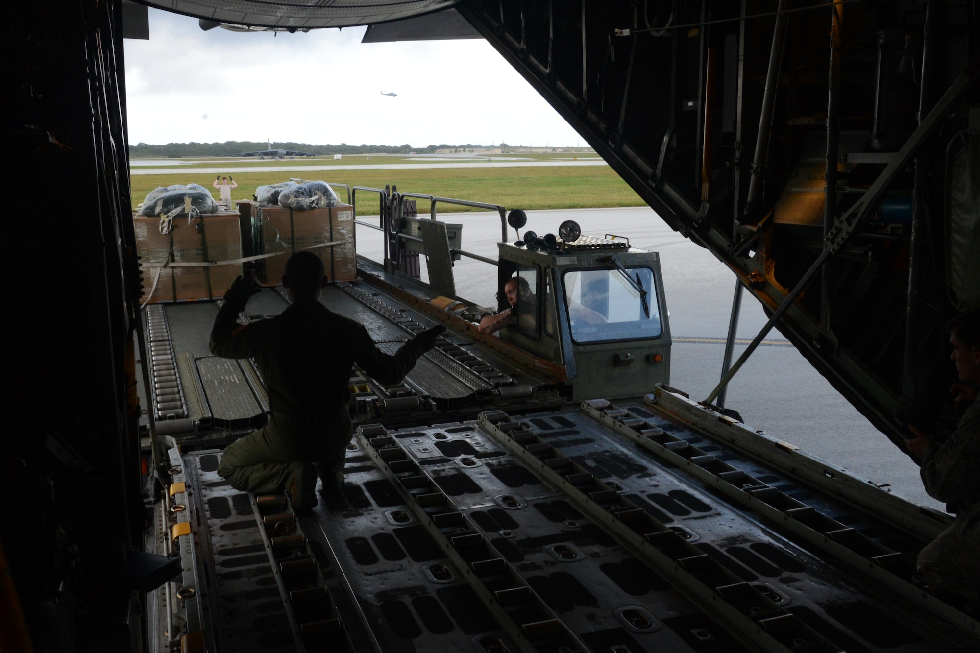 Airman 1st Class David Martinez, 36th Airlift Squadron loadmaster, directs a K-loader to align with a C-130 Hercules aircraft for Operation Christmas Drop at Andersen Air Force Base, Guam, Dec. 9, 2013. This year marks the 62nd year of Operation Christmas Drop, which began in 1952, making it the world's longest running airdrop mission. (U.S. Air Force photo by Airman 1st Class Emily A. Bradley/Released)