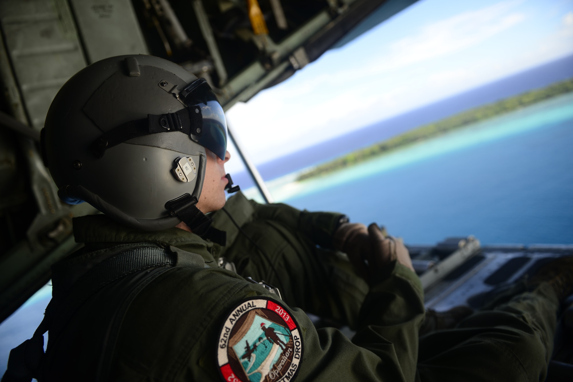 Staff Sgt. Renford Forbes, a loadmaster with the 36th Airlift Squadron, Yokota Air Base, Japan, looks out from the ramp of a C-130H aircraft while flying near the Faraulep Atoll, Federated States of Micronesia, during Operation Christmas Drop Dec. 10, 2013. This year marks the 62nd year of Operation Christmas Drop, which began in 1952, making it the world's longest running airdrop mission. Every December, C-130 Hercules crews from the 374th Airlift Wing at Yokota Air Base, Japan, partner with the 36th Wing at Andersen Air Force Base, Guam, to airlift food, supplies and toys to islanders throughout Micronesia. (U.S. Air Force photo by 2nd Lt. Jake Bailey/Released)