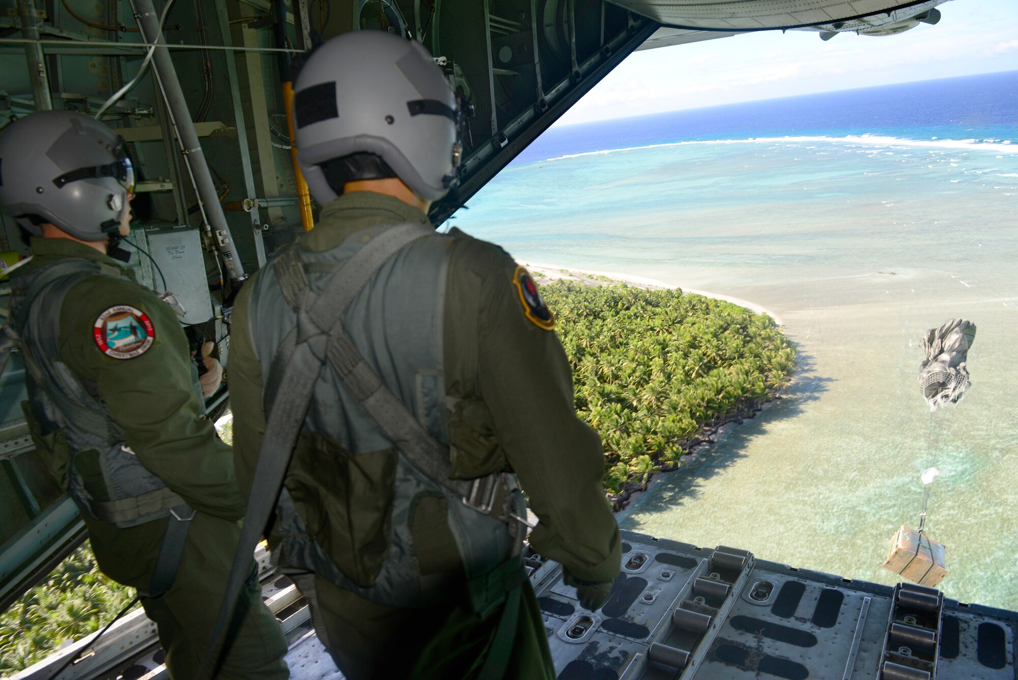 Staff Sgt. Renford Forbes, left, and Capt. Robert Tong deliver a low-cost, low-altitude airdrop bundle containing relief supplies from a C-130H aircraft to the island of Ifalik, Federated States of Micronesia, during Operation Christmas Drop Dec. 10, 2013. Forbes is a loadmaster assigned to the 36th Airlift Squadron, Yokota Air Base, Japan, and Tong is a flight surgeon assigned to the 36th Medical Group, Andersen Air Force Base, Guam. This year marks the 62nd year of Operation Christmas Drop, which began in 1952, making it the world's longest running airdrop mission. Every December, C-130 Hercules crews from the 374th Airlift Wing at Yokota Air Base, Japan, partner with the 36th Wing at Andersen Air Force Base, Guam, to airlift food, supplies and toys to islanders throughout Micronesia. (U.S. Air Force photo by 2nd Lt. Jake Bailey/Released)