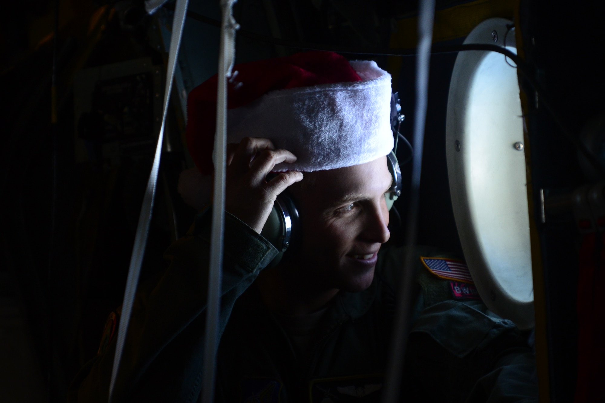 Staff Sgt. Renford Forbes, a loadmaster with the 36th Airlift Squadron, looks out an aircraft window while monitoring radio traffic aboard a C-130H aircraft over the Federated States of Micronesia during Operation Christmas Drop Dec. 10, 2013. This year marks the 62nd year of Operation Christmas Drop, which began in 1952, making it the world's longest running airdrop mission. Every December, C-130 Hercules crews from the 374th Airlift Wing at Yokota Air Base, Japan, partner with the 36th Wing at Andersen Air Force Base, Guam, to airlift food, supplies and toys to islanders throughout Micronesia. (U.S. Air Force photo by 2nd Lt. Jake Bailey/Released)