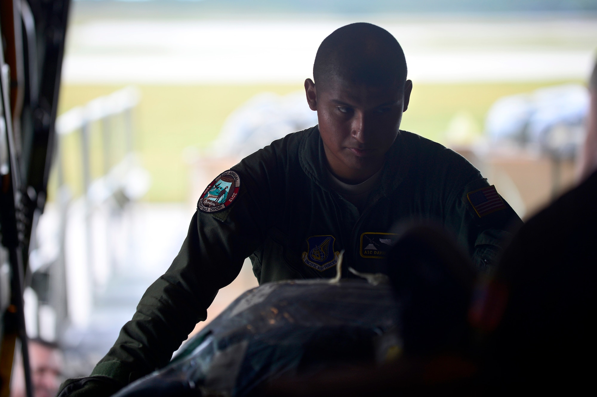 Airman 1st Class David Martinez, a loadmaster assigned to the 36th Airlift Squadron, Yokota Air Base, Japan, pushes a low-cost, low-altitude airdrop bundle onto a C-130H aircraft at Andersen Air Force Base, Guam, during Operation Christmas Drop, Dec. 9, 2013. This year marks the 62nd year of Operation Christmas Drop, which began in 1952, making it the world's longest running airdrop mission. (U.S. Air Force photo by 2nd Lt. Jake Bailey/Released)