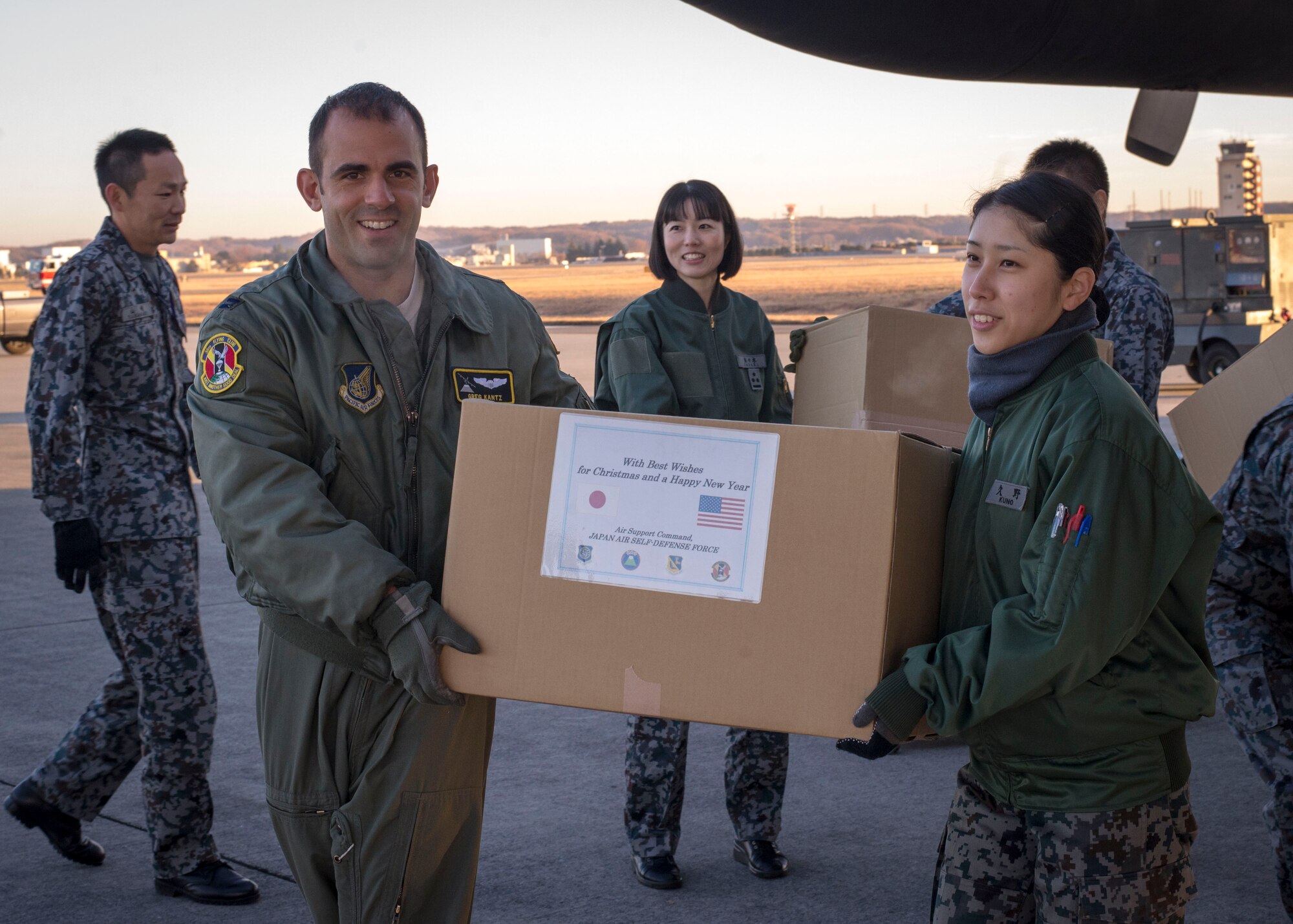A Japanese and U.S. Airman carry a box of donated goods provided by the Japan Air Self Defense Force aboard a U.S. C-130 Hercules at Yokota Air Base, Japan, Dec. 13, 2013. The goods will be dropped over several islands in the Federated States of Micronesia as a part of Operation Christmas Drops. (U.S. Air Force photo by Captain Raymond Geoffroy/Released)