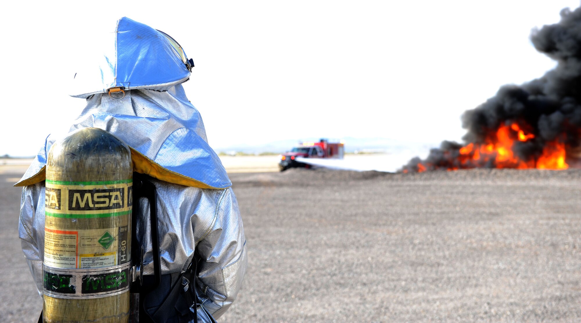 A U.S. Air Force fire fighter from the 355th Civil Engineering Squadron looks on as a rapid intervention vehicle battles a controlled aircraft fire during a training exercise at Davis-Monthan Air Force Base, Ariz. Dec. 10, 2013. Both D-M and Tucson International Airport participate in at least one joint training exercise per year. (U.S. Air Force photo by Airman 1st Class Chris Drzazgowski/Released)
