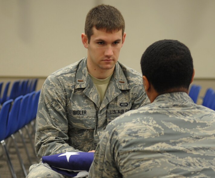 2nd Lt. Alexander Sigler, Honor Guard member, is presented a folded flag from Senior Airman Shawn Morgan during a practice ceremony on Barksdale Air Force Base, La., Dec. 12, 2013. Honor Guard Airmen prepare for moments like this when strong, military bearing is a necessity. It takes anywhere from four to six weeks for new Airmen to become fully Honor Guard qualified. Once trained, they receive their full uniforms and are then eligible to begin performing details. (U.S. Air Force photo/Senior Airman Kristin High)