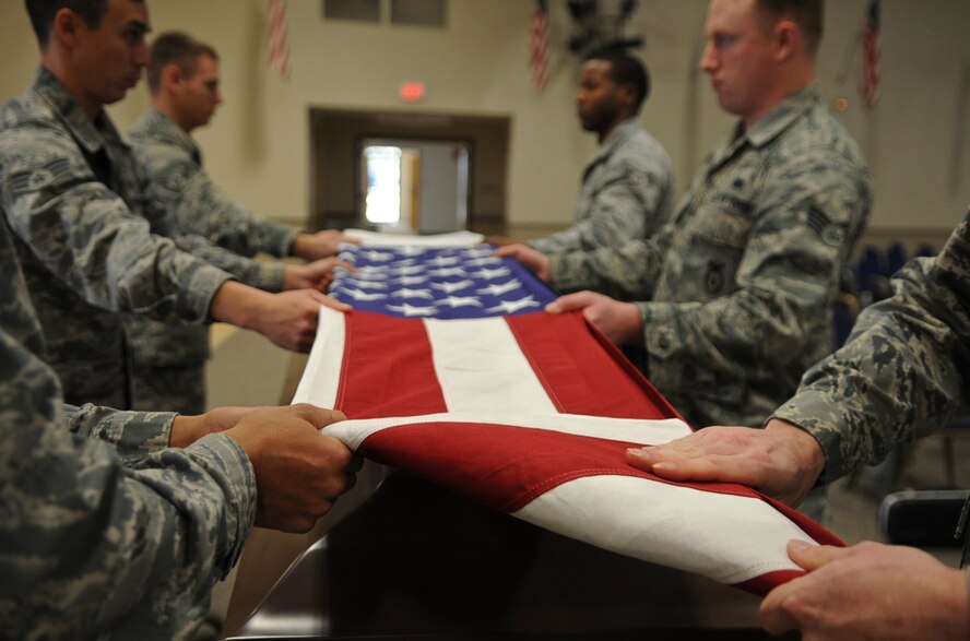 Members from the Barksdale Honor Guard begin a flag folding procedure on Barksdale Air Force Base, La., Dec. 12, 2013. The flag is carefully folded into the shape of a tri-cornered hat, to signify the hats worn by colonial soldiers during the war for Independence. (U.S. Air Force photo/Senior Airman Kristin High)