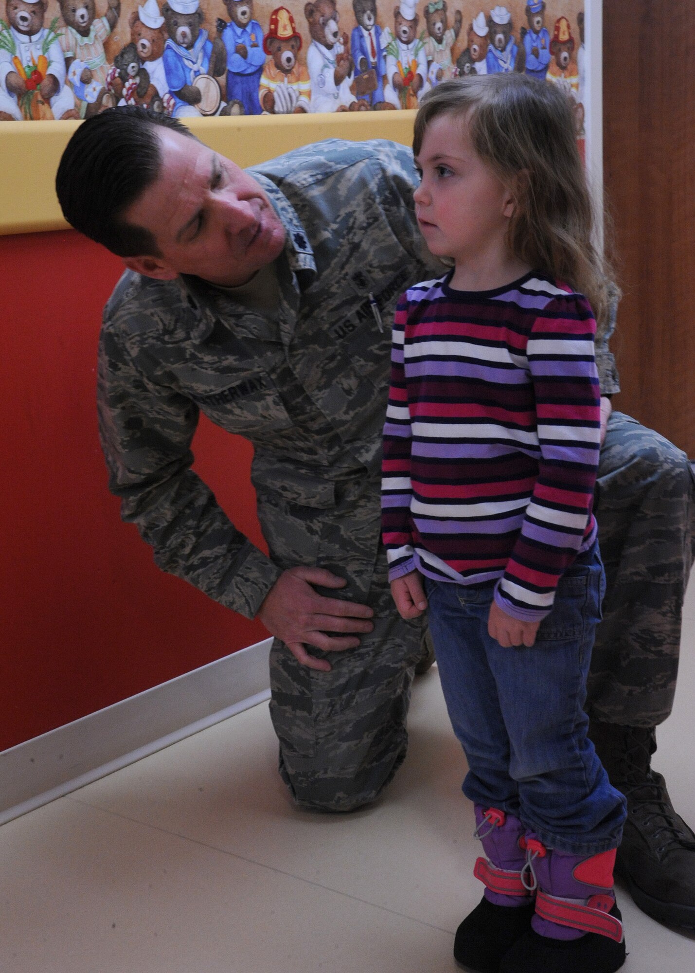 Lt. Col. John Weatherwax, 341st Medical Operations Squadron pediatric nurse, asks to Lauren Bicknell, 4, how old she is, as her mother watches nearby, at the Malmstrom Clinic on Dec. 10. Weatherwax was the winner of the Air Force Global Strike Command Privileged Advanced Practice Nurse Award. (U.S. Air Force photo/Senior Airman Cortney Paxton)
