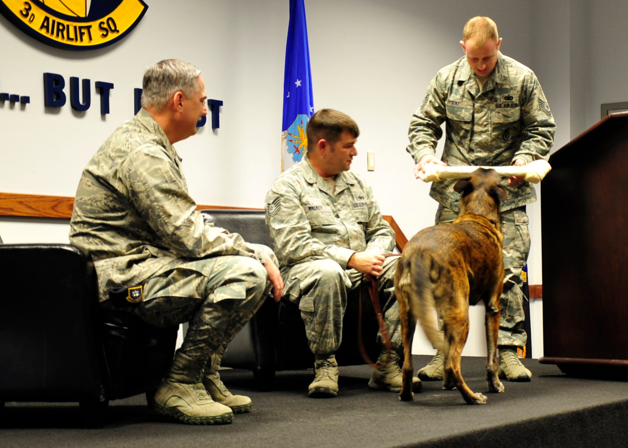 Tech. Sgt. Adam Fike, 436th Security Forces Squadron kennel master, presents Lance, 436th SFS military working dog, with a rawhide bone as a retirement gift Dec. 11, 2013, at Dover Air Force Base, Del. Lance has been on four deployments to the Middle East and assigned to seven different military dog handlers during his nine-year career. (U.S. Air Force photo/Airman 1st Class William Johnson)