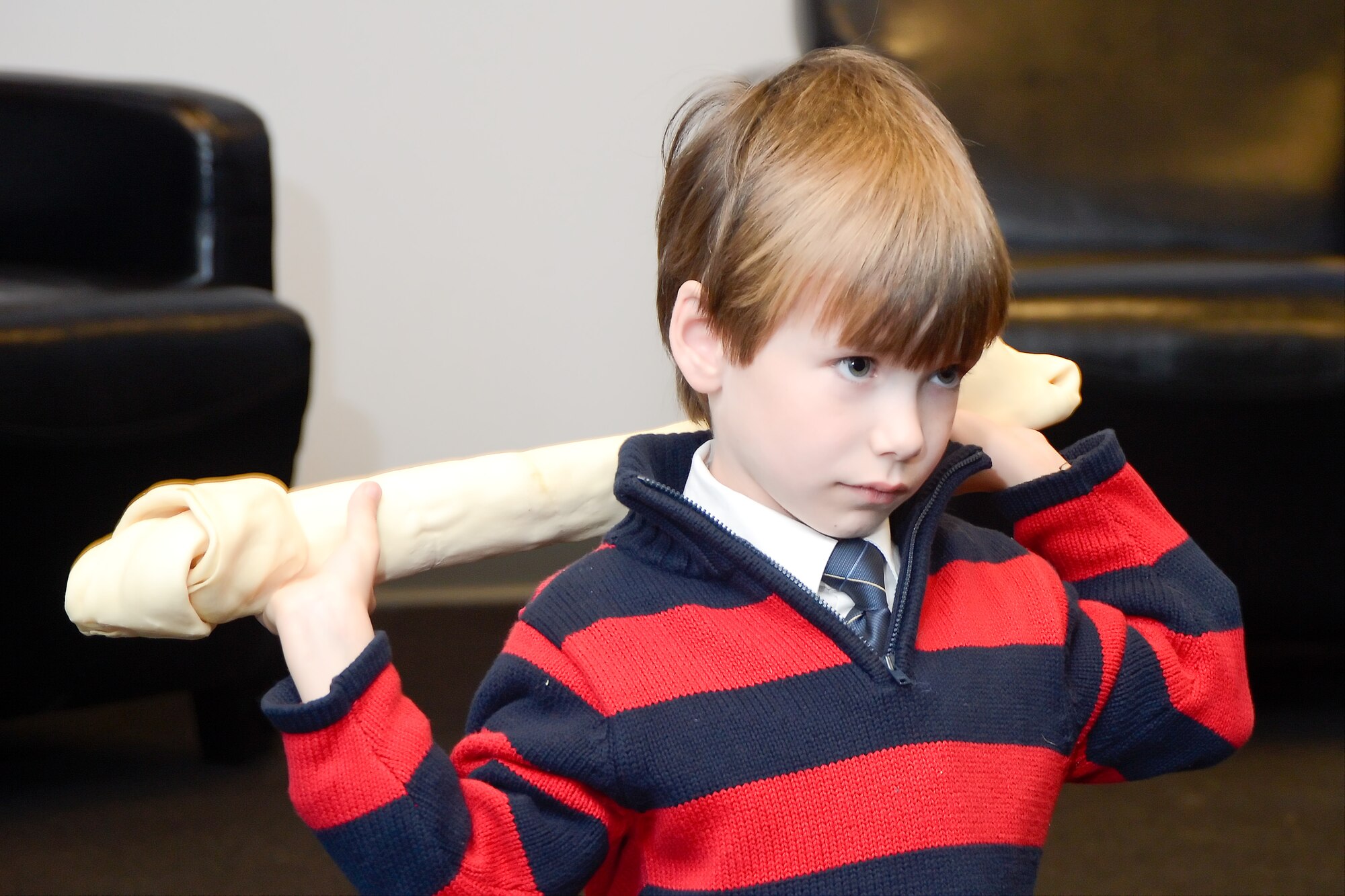 Gavin Walker, 7, the son of Technical Sgt. Ryan Walker, 436th Security Forces Squadron, holds a raw hide chew toy over his back following the retirement of military working dog, Llance, on Dec. 11, 2013, Dover Air Force Base, Del. The Walker family adopted Llance and one of the first retirement gifts given to Llance was the giant rawhide chew. Llance served nine years on active duty service in the United States Air Force. (U.S. Air Force photo/Greg L. Davis)
