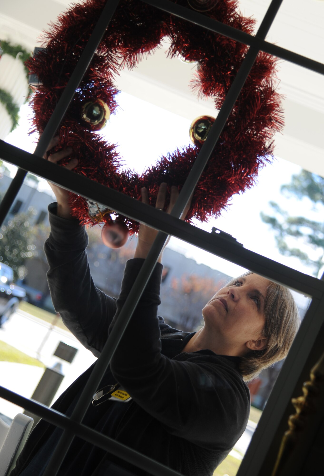 Beth Harrell, a local Biloxi business employee, hangs a wreath on a window while decorating the Fisher House with Christmas ornaments Dec. 12, 2013, at Keesler Air Force Base, Miss.  Every year a local business volunteers to decorate the house. The Fisher House Foundation is best known for a network of comfort homes where military and veterans’ families can stay at no cost while a loved one is receiving treatment.  (U.S. Air Force photo by Kemberly Groue)