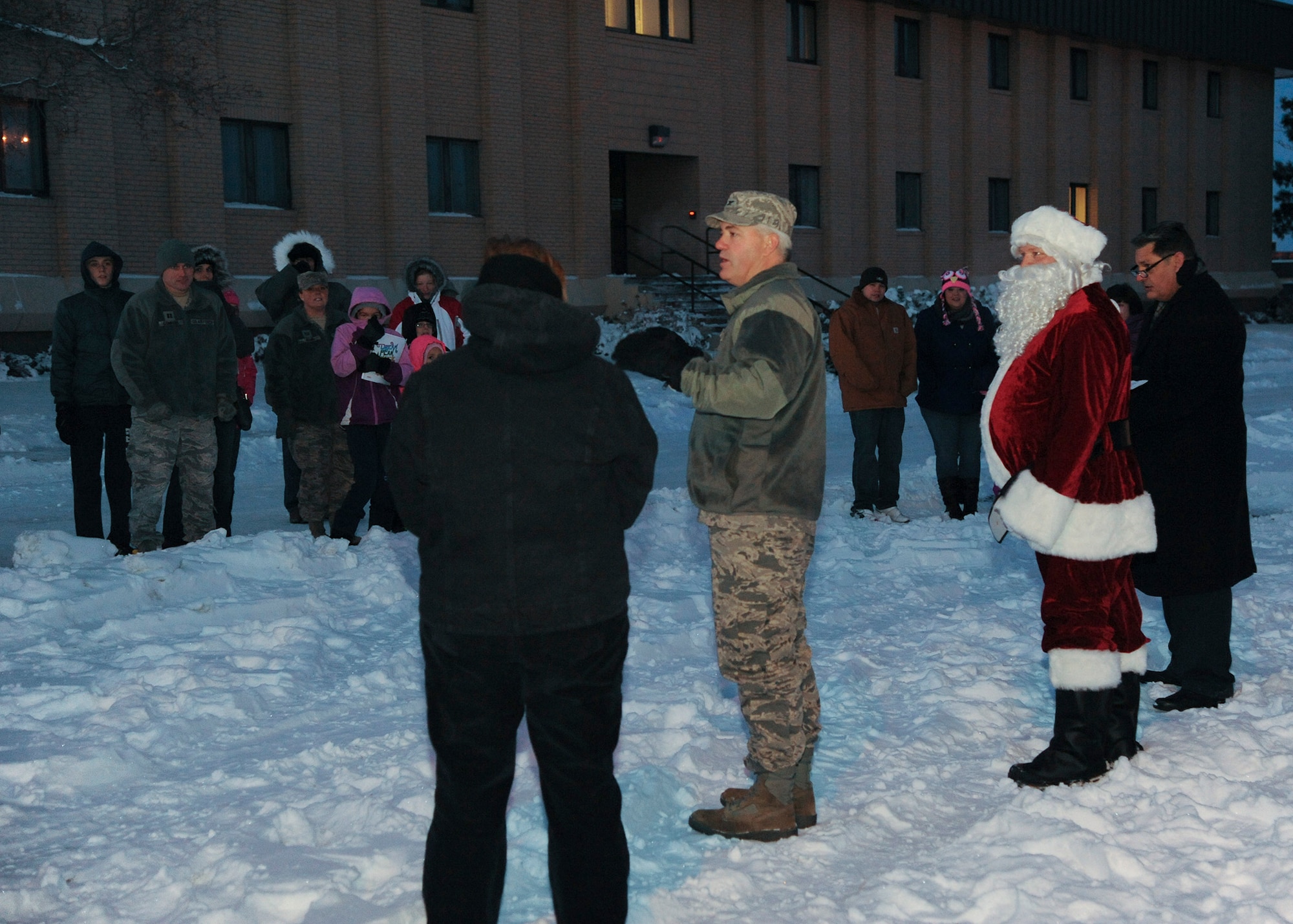 Col. Mark Schuler, 341st Operations Group commander (center), and Santa Claus greet the audience at the tree-lighting ceremony in front of Bldg. 1191 on Dec. 5.  Following the tree-lighting ceremony, Team Malmstrom members were able to go inside the Grizzly Bend for some snacks and to hear the winners of the Holiday Card Contest.  (U.S. Air Force photo/Senior Airman Cortney Paxton)