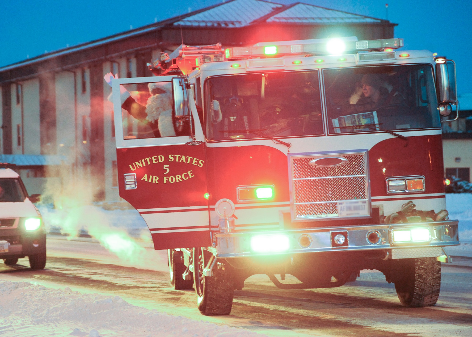 Santa Claus arrives at the tree-lighting ceremony in a fire truck and waves at Team Malmstrom members attending the ceremony. He and the 341st Operations Group commander lit the tree, marking the beginning of the base's winter holiday celebrations.  (U.S. Air Force photo/Senior Airman Cortney Paxton)